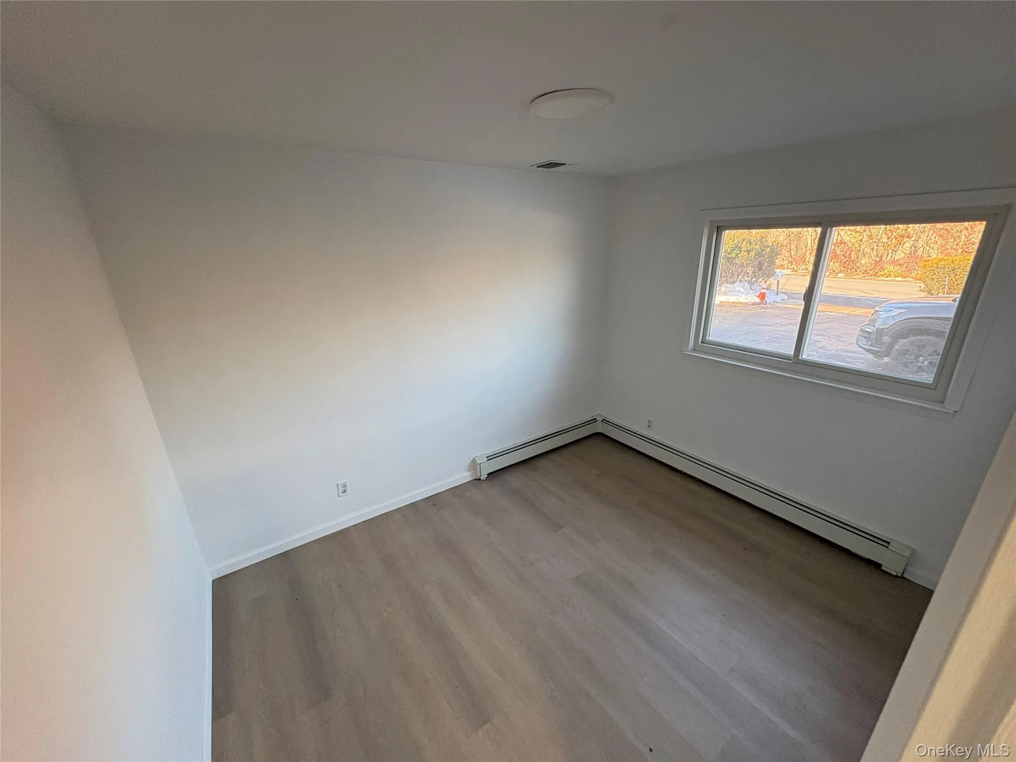 Empty room with wood finished floors and a baseboard radiator Empty room with wood finished floors and a baseboard radiator