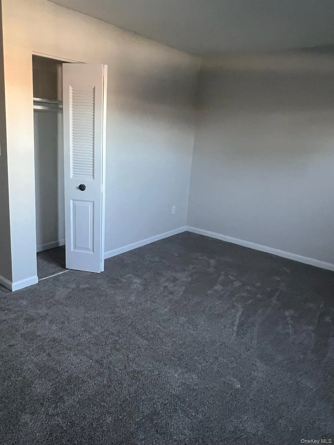 Unfurnished bedroom featuring a closet and dark colored carpet Unfurnished bedroom featuring a closet and dark colored carpet