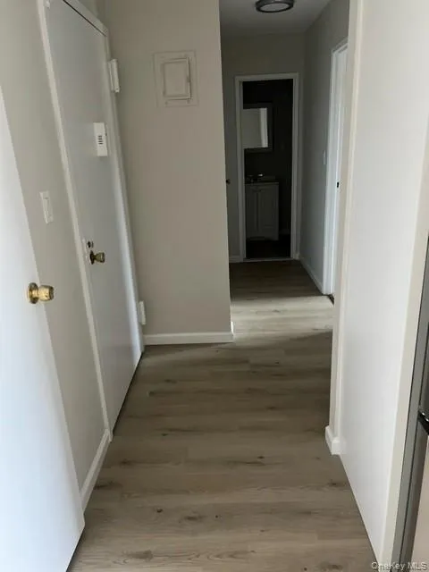 Corridor featuring light wood-style flooring and baseboards Corridor featuring light wood-style flooring and baseboards