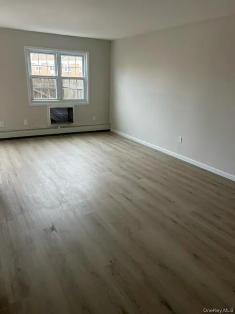 Spare room featuring wood finished floors and a baseboard heating unit Spare room featuring wood finished floors and a baseboard heating unit