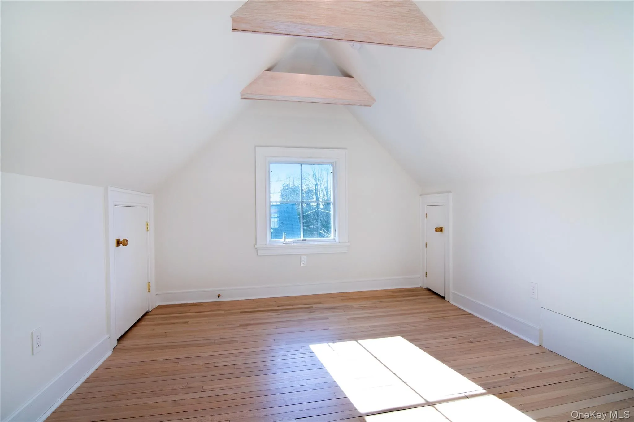 Upper-level bedroom featuring hardwood flooring and vaulted ceiling Upper-level bedroom featuring hardwood flooring and vaulted ceiling