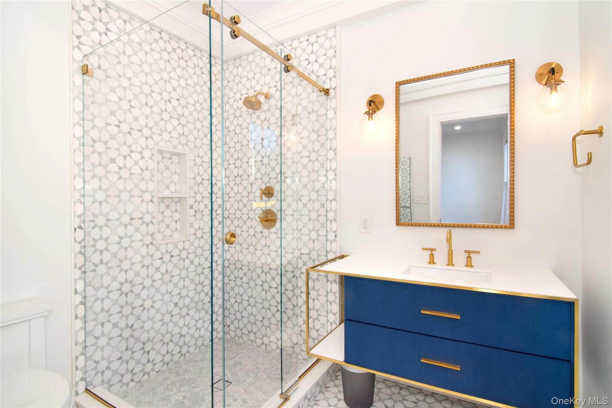 Primary bedroom features glass-enclosed shower with patterned tile and warm brass finishes Primary bedroom features glass-enclosed shower with patterned tile and warm brass finishes