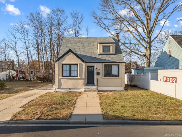 View of front of home with a shingled roof, a chimney, a front yard, and stucco siding