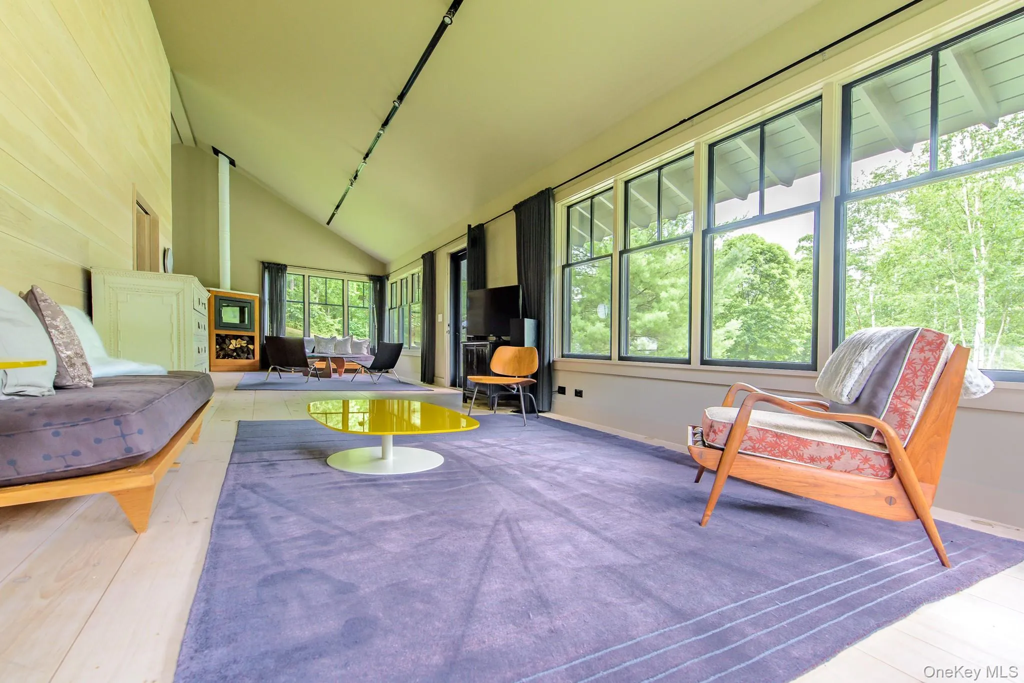 Sunroom / solarium featuring high vaulted ceiling, a wood stove, and hardwood / wood-style floors Sunroom / solarium featuring high vaulted ceiling, a wood stove, and hardwood / wood-style floors