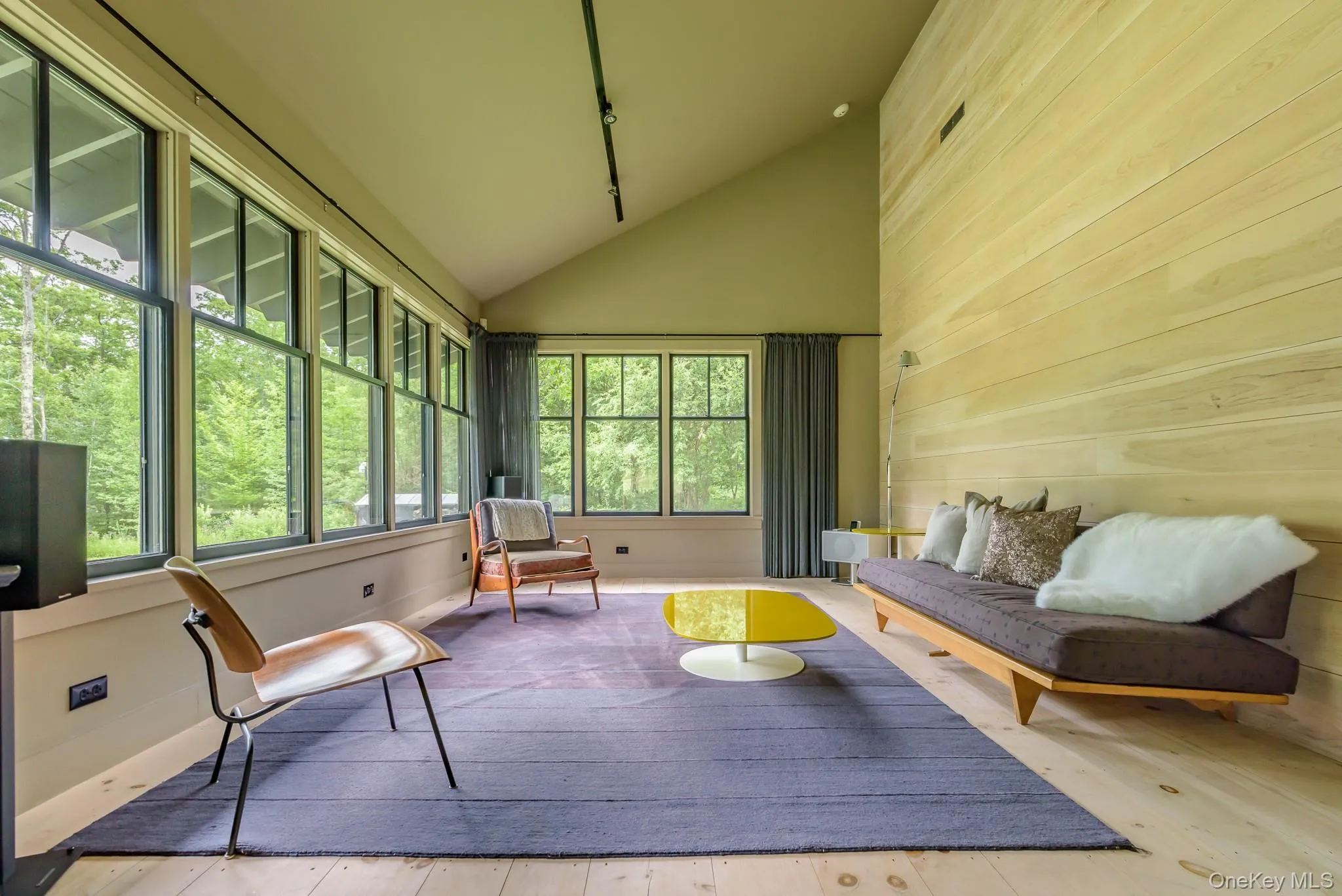 Sunroom / solarium featuring wood walls, high vaulted ceiling, and wood-type flooring Sunroom / solarium featuring wood walls, high vaulted ceiling, and wood-type flooring