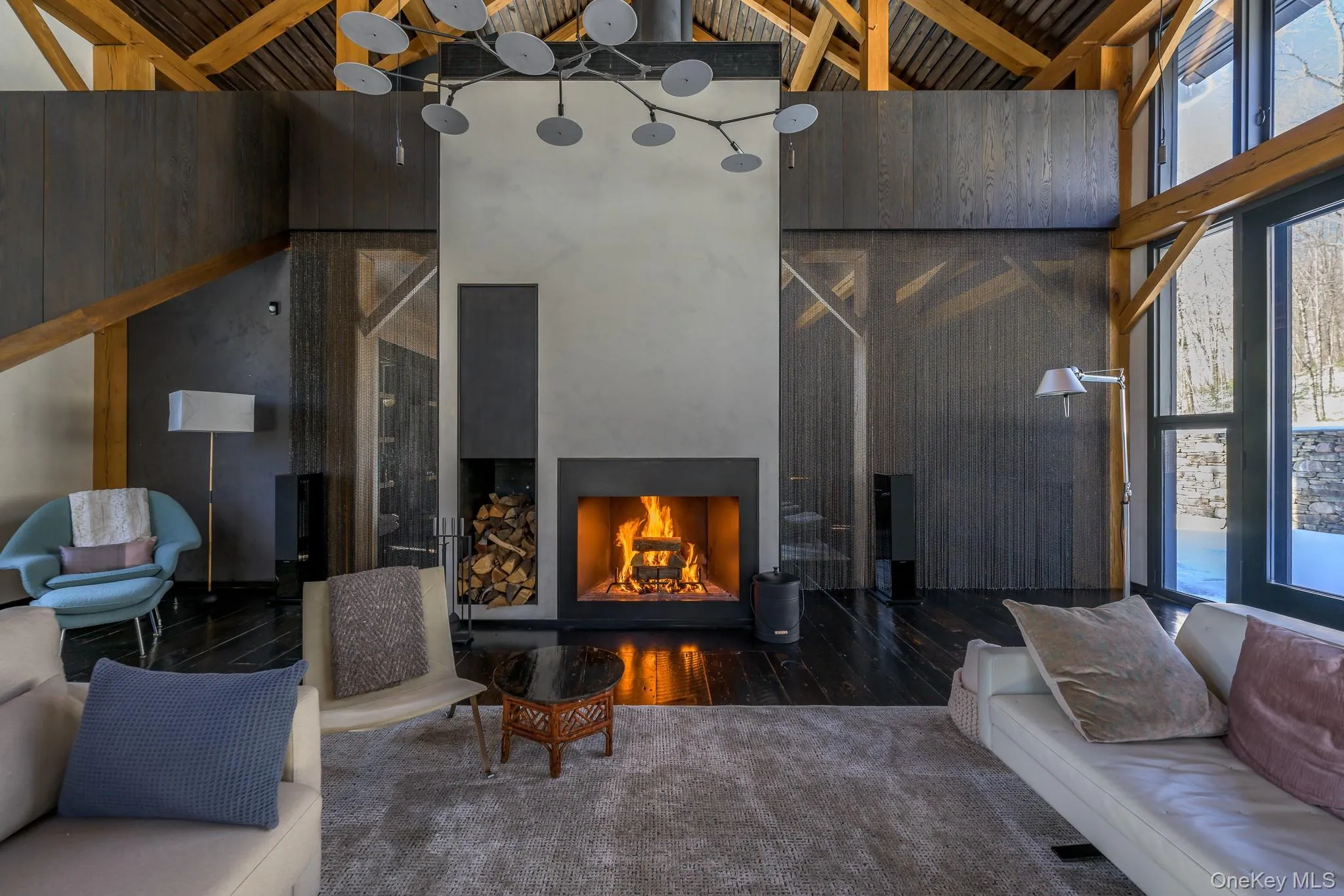 Living room featuring a warm lit fireplace, healthy amount of natural light, hardwood / wood-style floors, high vaulted ceiling, and wooden walls Living room featuring a warm lit fireplace, healthy amount of natural light, hardwood / wood-style floors, high vaulted ceiling, and wooden walls