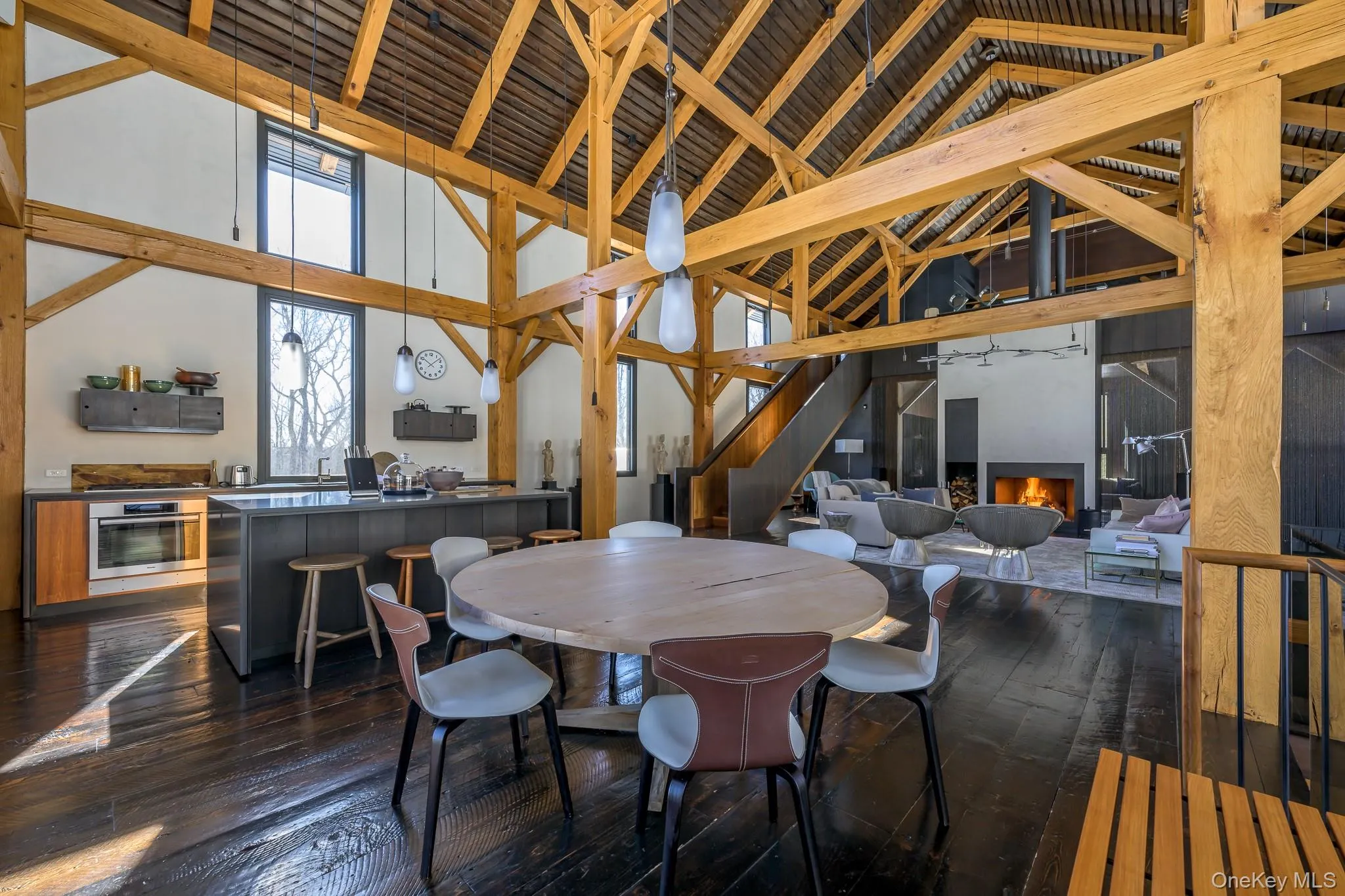 Dining space with a warm lit fireplace, dark wood-type flooring, high vaulted ceiling, and beam ceiling Dining space with a warm lit fireplace, dark wood-type flooring, high vaulted ceiling, and beam ceiling