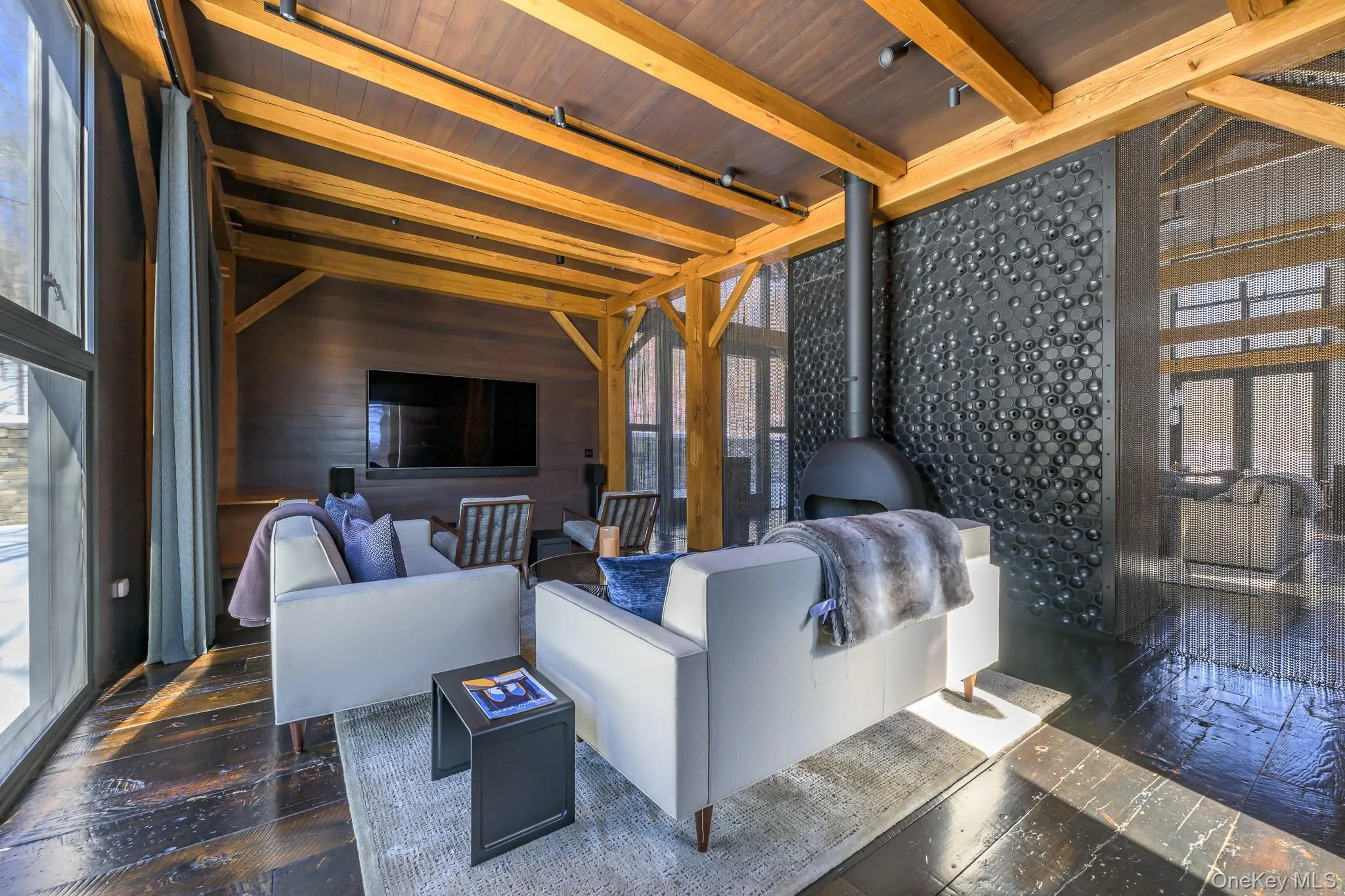 Living area with wooden walls, plenty of natural light, wood ceiling, and dark wood finished floors Living area with wooden walls, plenty of natural light, wood ceiling, and dark wood finished floors