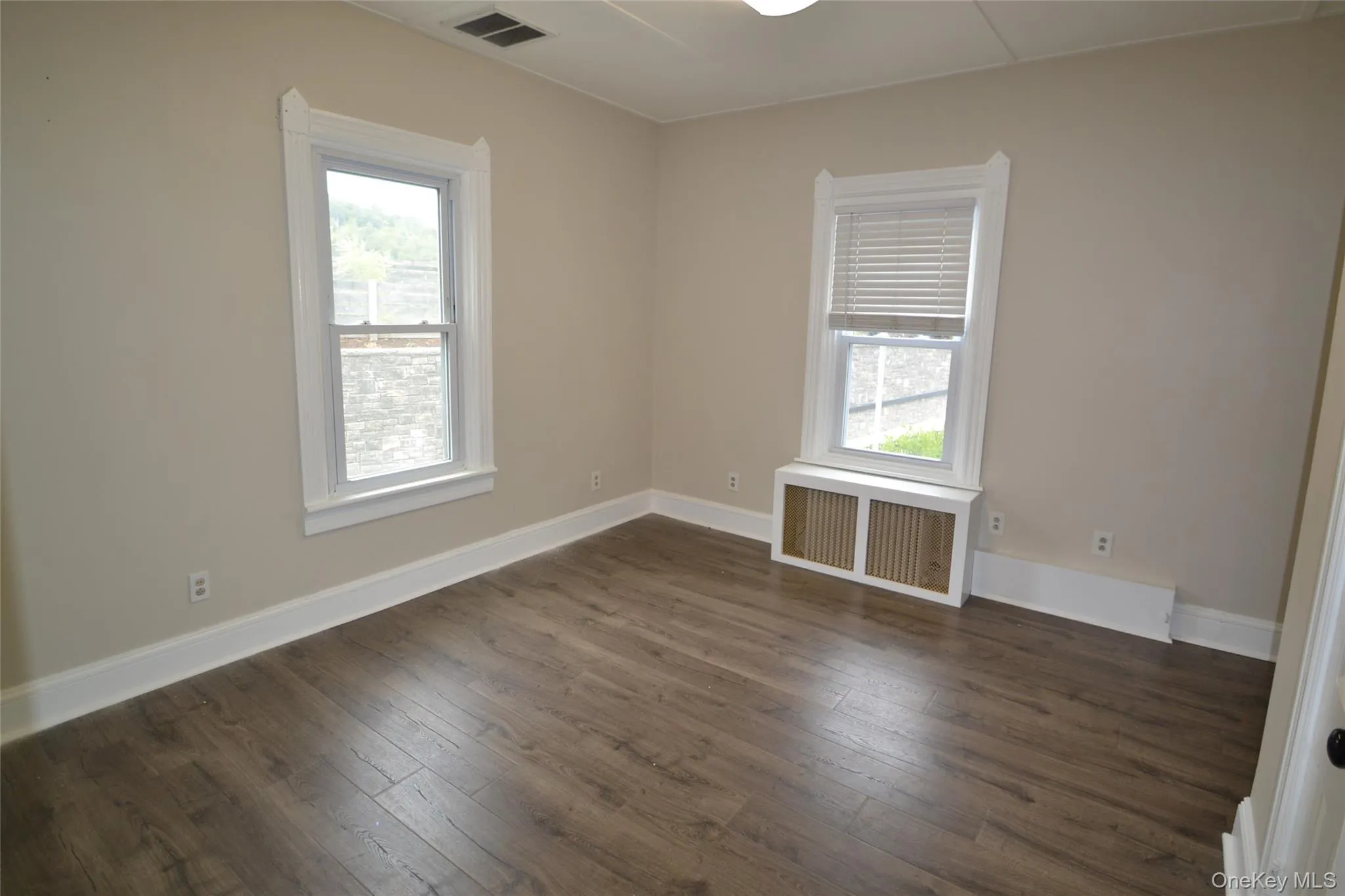 Unfurnished room featuring radiator and dark wood-style floors Unfurnished room featuring radiator and dark wood-style floors