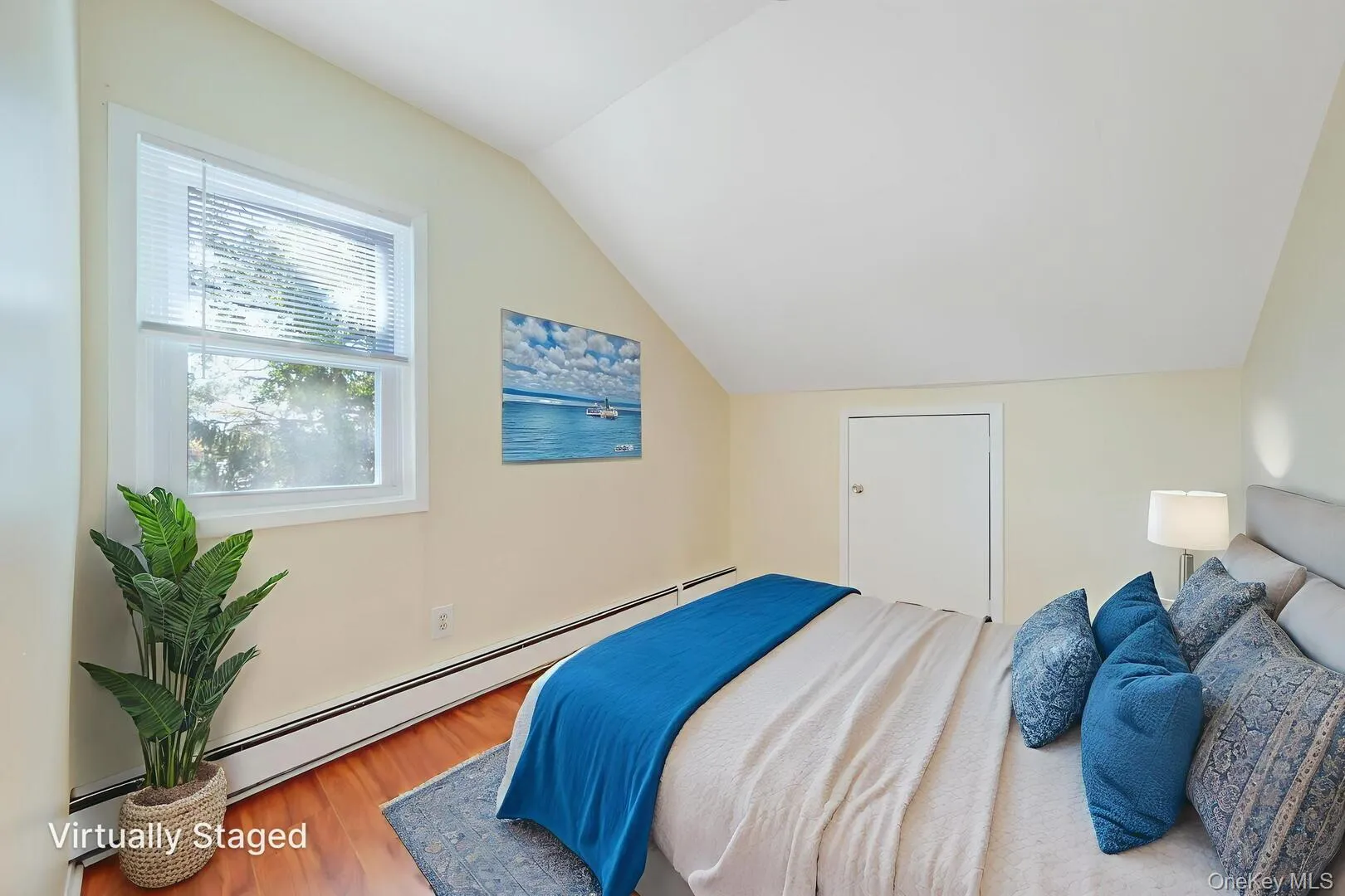 Bedroom featuring a baseboard heating unit, vaulted ceiling, and wood finished floors Bedroom featuring a baseboard heating unit, vaulted ceiling, and wood finished floors