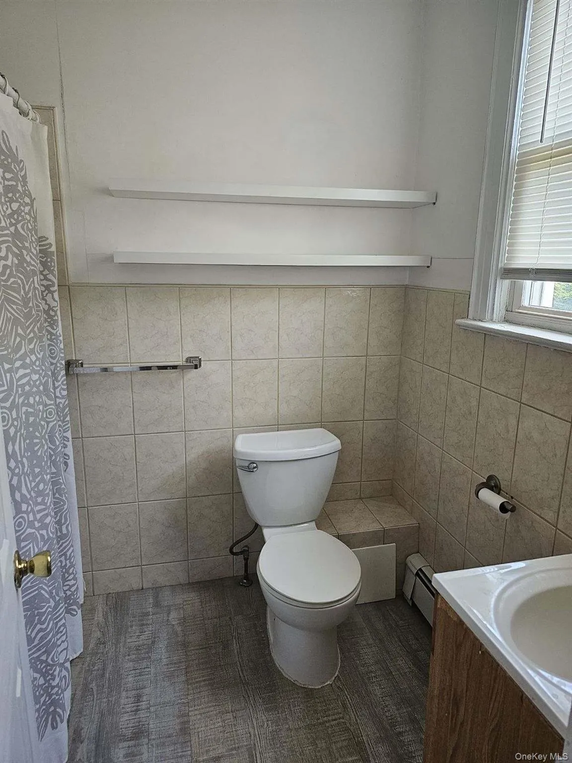 Bathroom featuring vanity, baseboard heating, a shower with shower curtain, and tile walls Bathroom featuring vanity, baseboard heating, a shower with shower curtain, and tile walls
