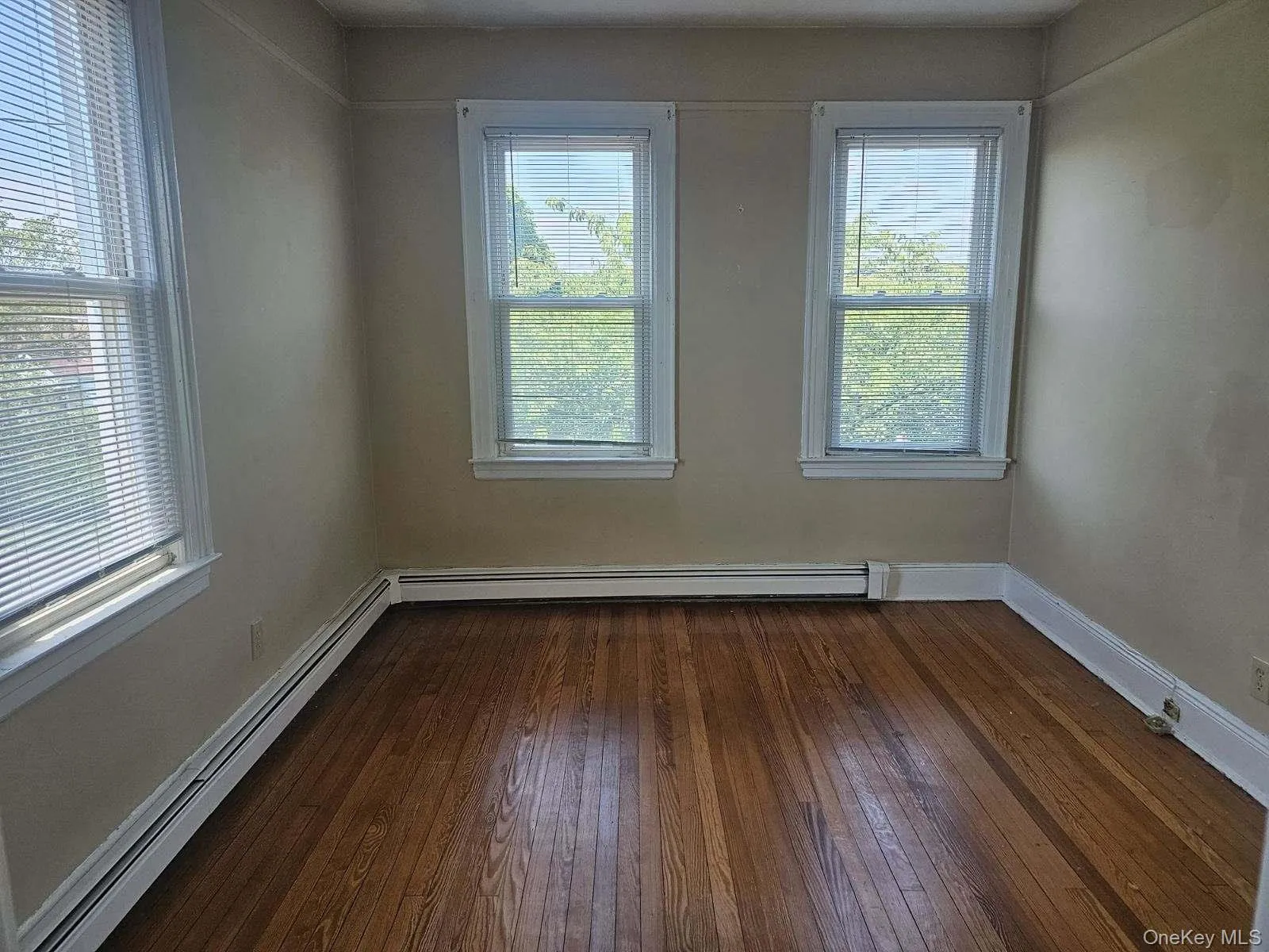 Empty room with baseboard heating and dark wood-style floors Empty room with baseboard heating and dark wood-style floors