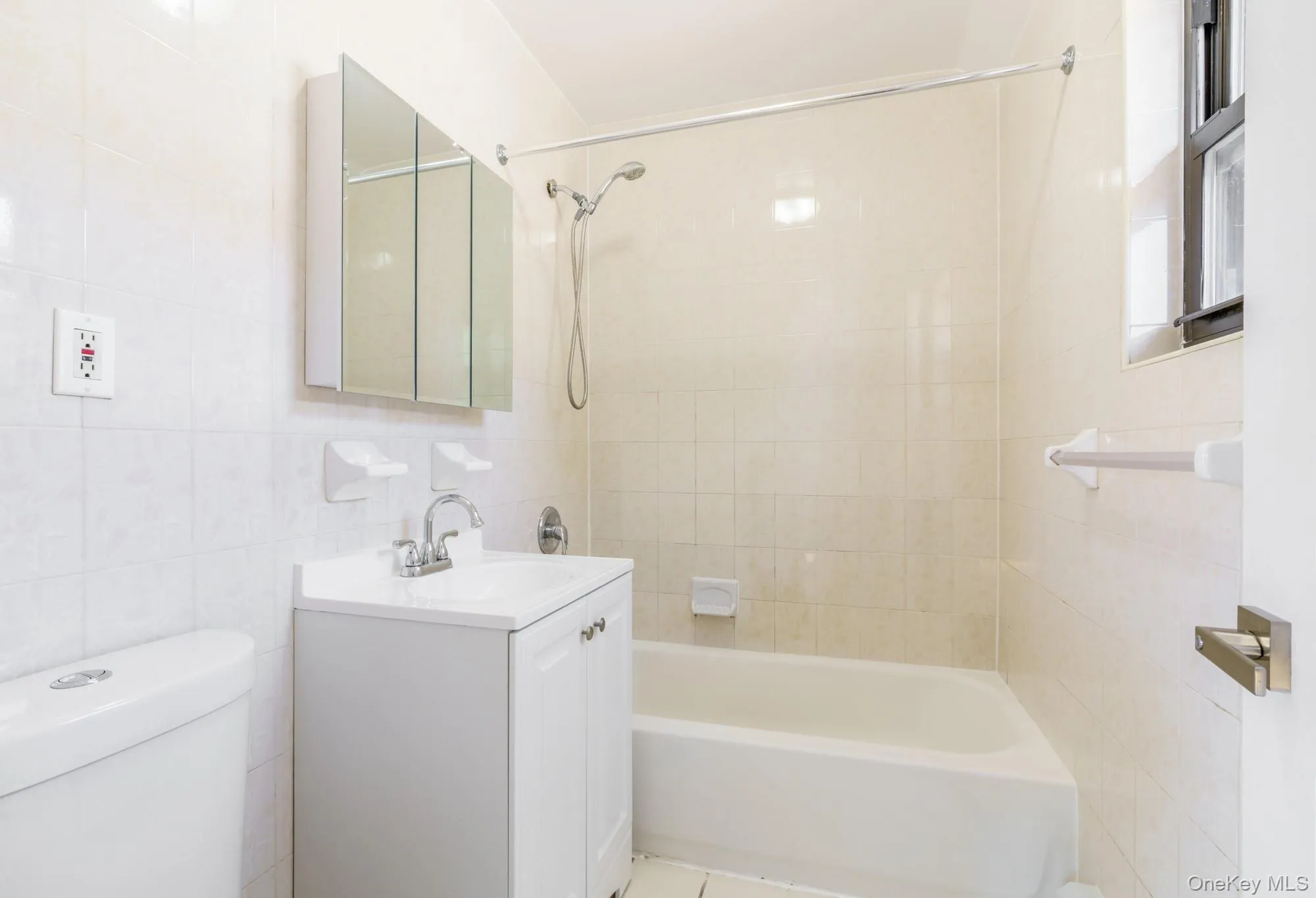 Bathroom with tile walls, vanity, and shower / bath combination Bathroom with tile walls, vanity, and shower / bath combination