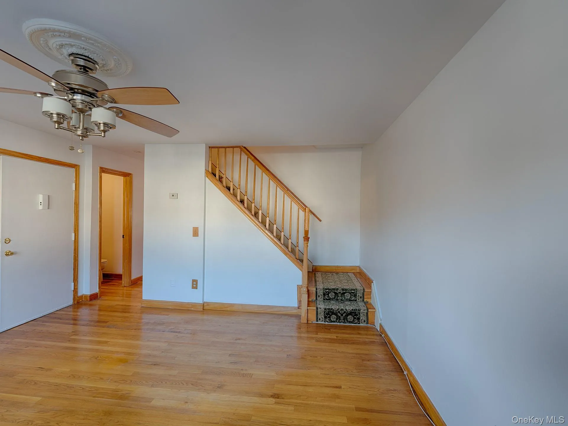 Unfurnished living room with light wood-type flooring, stairs, and ceiling fan Unfurnished living room with light wood-type flooring, stairs, and ceiling fan