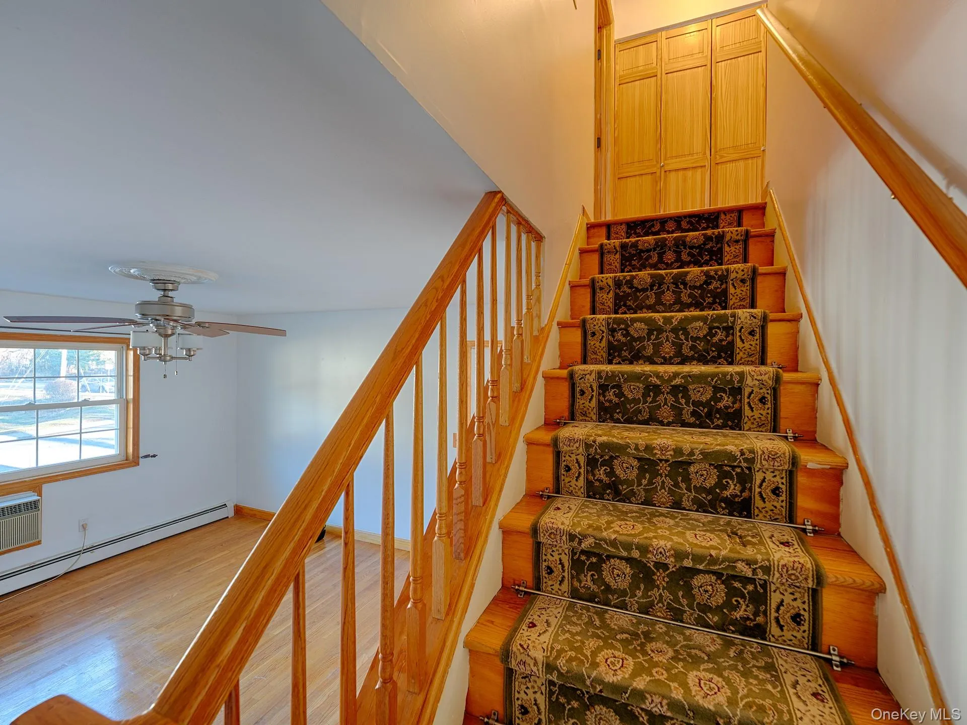 Stairs with wood finished floors, ceiling fan, and a wall mounted AC Stairs with wood finished floors, ceiling fan, and a wall mounted AC