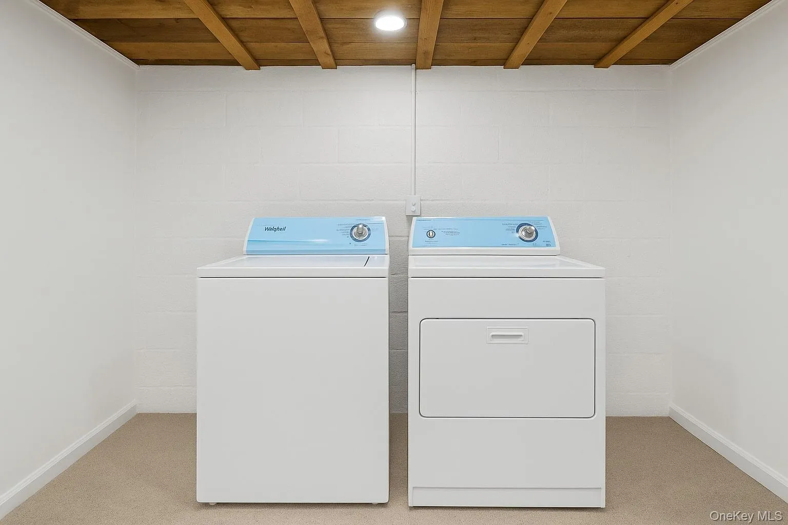 Laundry room featuring wood ceiling, washing machine and dryer, light colored carpet, and baseboards Laundry room featuring wood ceiling, washing machine and dryer, light colored carpet, and baseboards