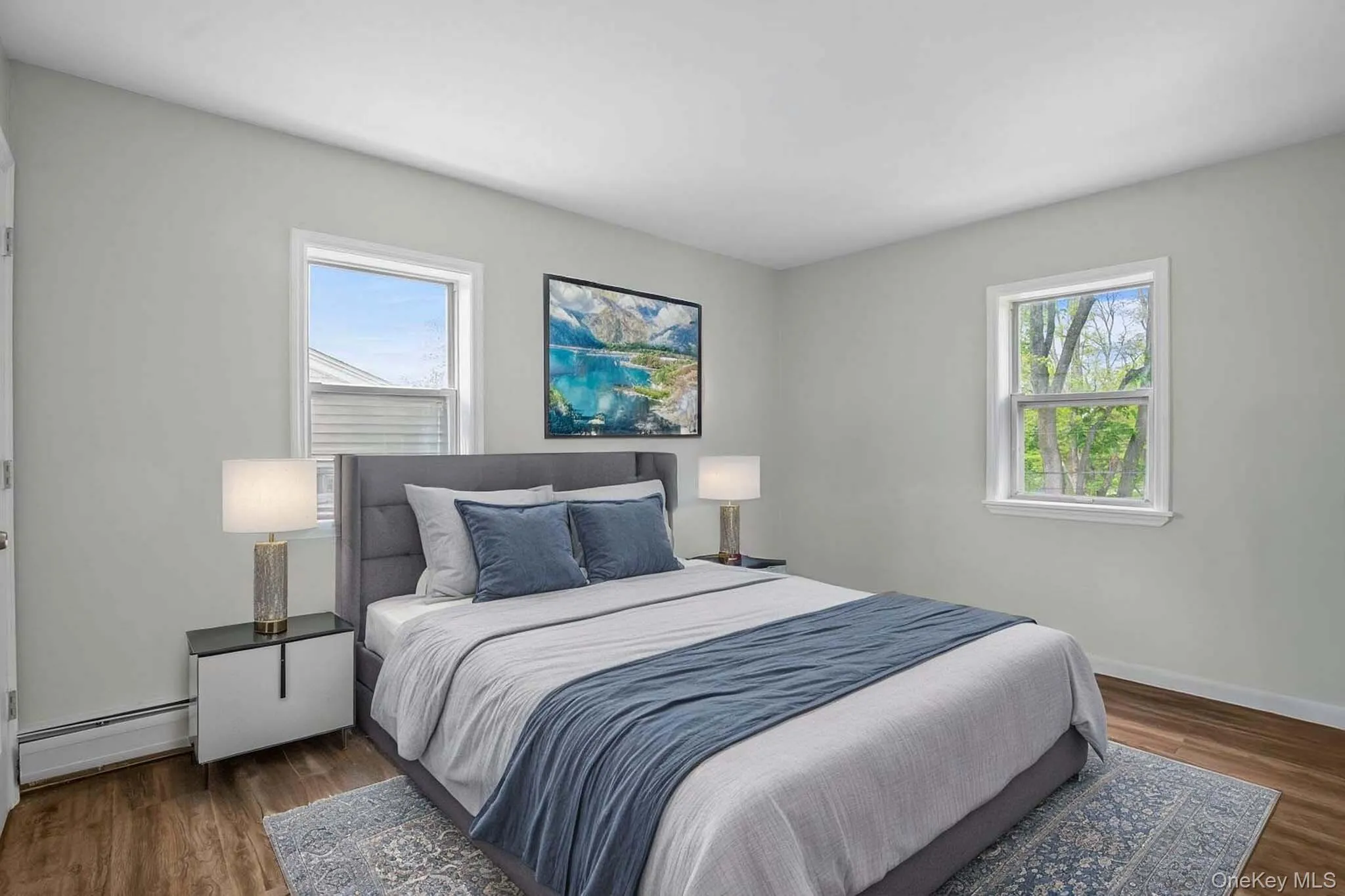 Bedroom with baseboard heating, multiple windows, wood finished floors, and baseboards. Virtually Staged Bedroom with baseboard heating, multiple windows, wood finished floors, and baseboards. Virtually Staged