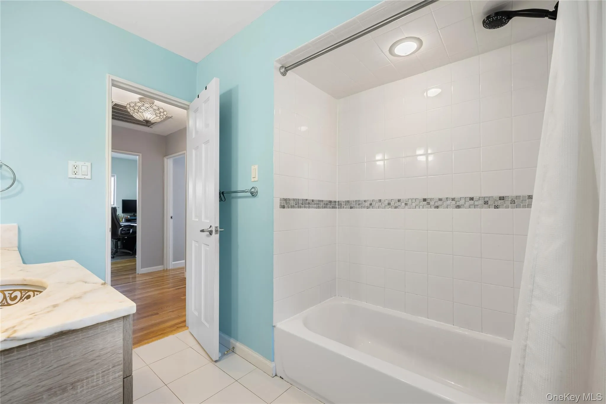 Full bathroom featuring vanity, shower / bath combo, and light tile patterned floors Full bathroom featuring vanity, shower / bath combo, and light tile patterned floors