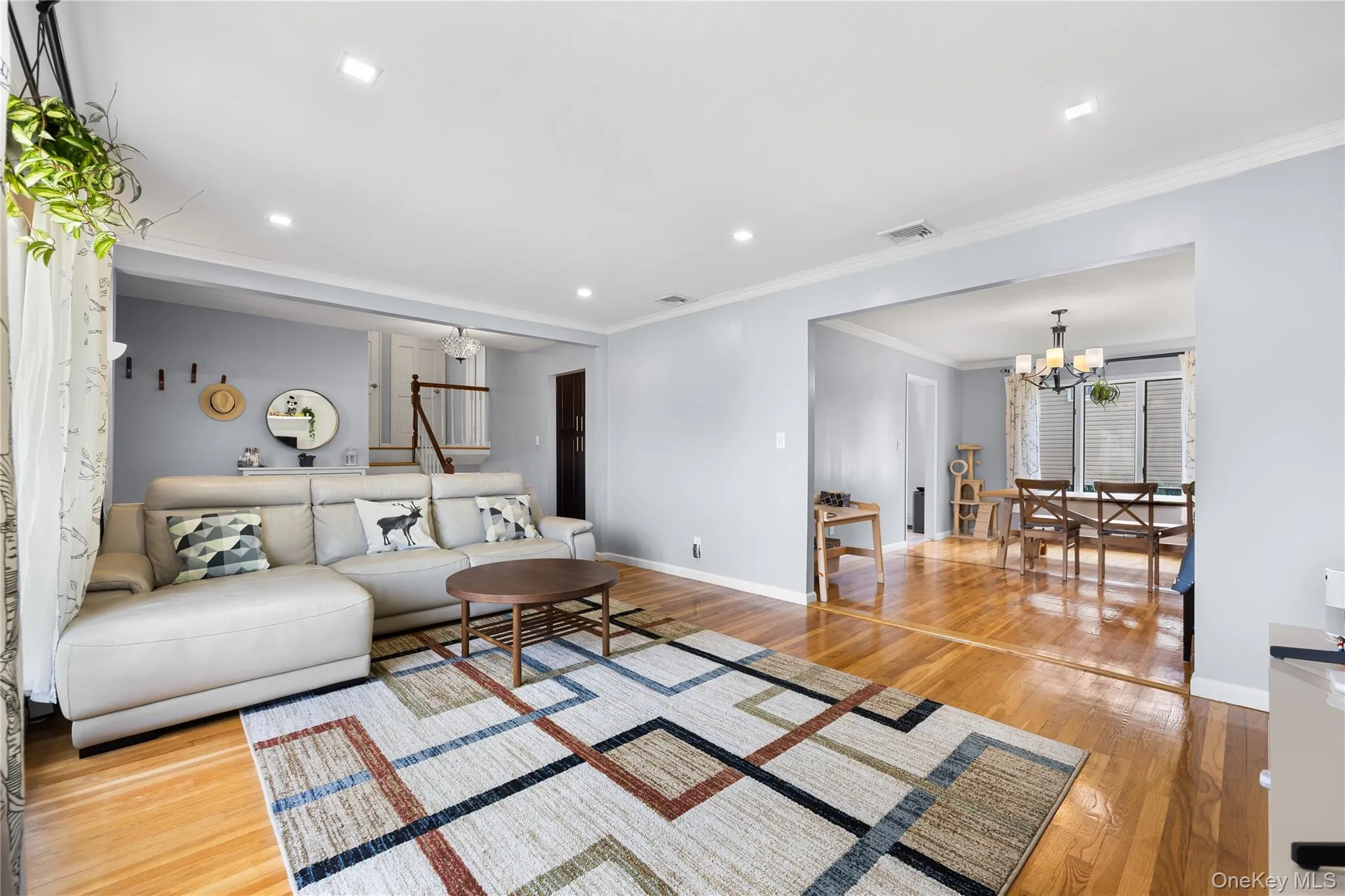 Living area featuring a chandelier, light wood-type flooring, recessed lighting, and ornamental molding Living area featuring a chandelier, light wood-type flooring, recessed lighting, and ornamental molding
