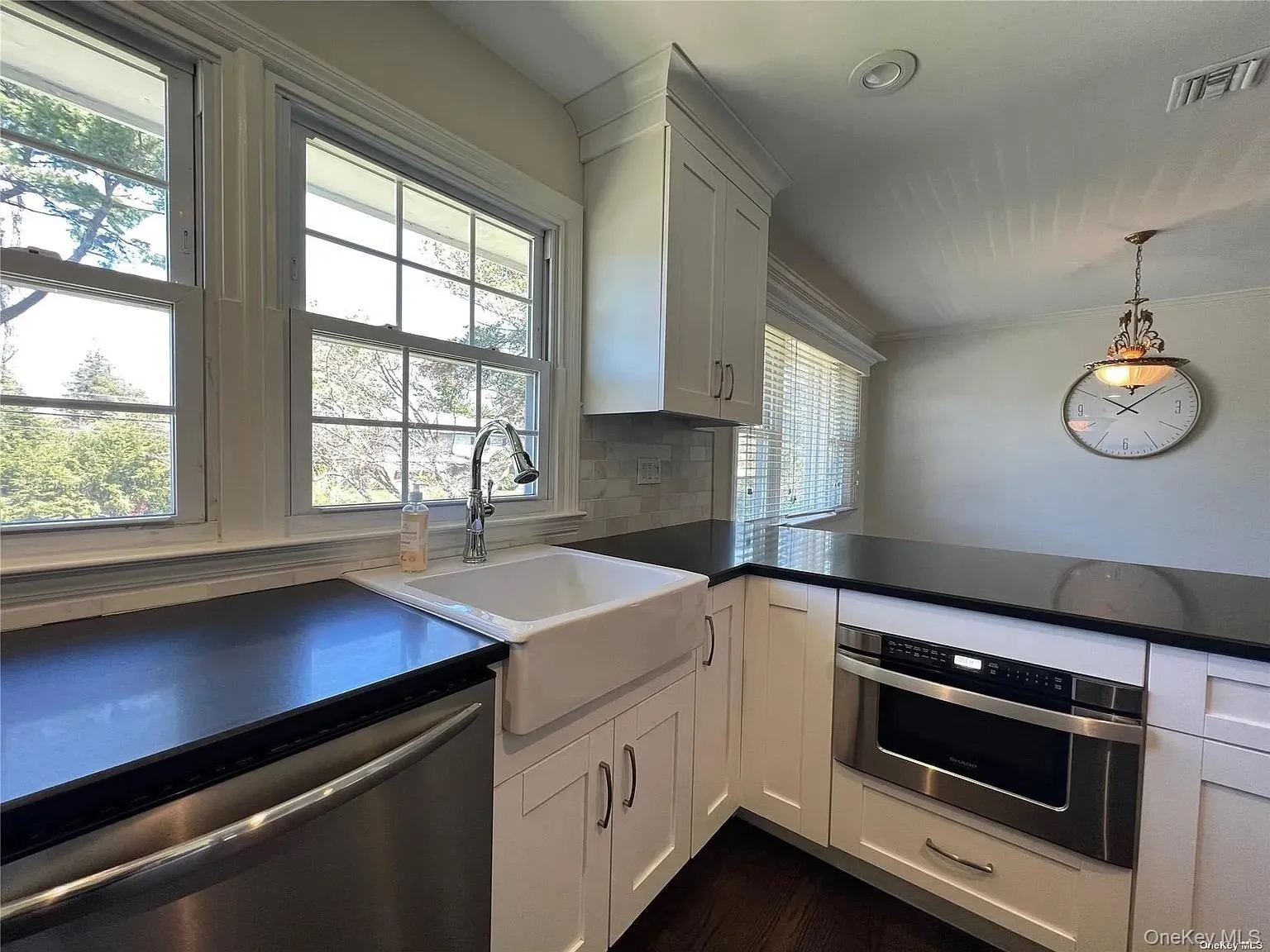 Kitchen featuring white cabinetry, appliances with stainless steel finishes, backsplash, and hanging light fixtures Kitchen featuring white cabinetry, appliances with stainless steel finishes, backsplash, and hanging light fixtures