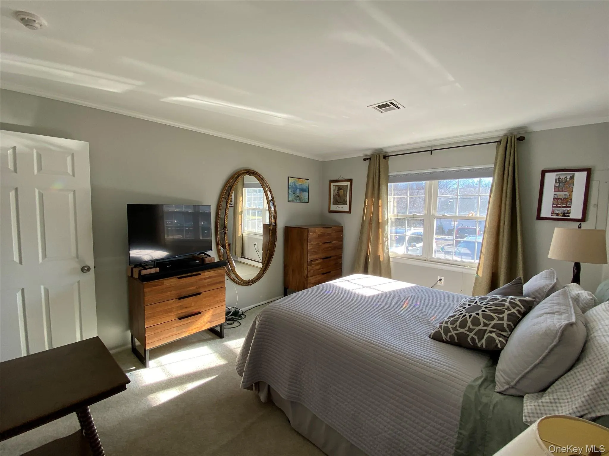 Carpeted bedroom featuring multiple windows and crown molding Carpeted bedroom featuring multiple windows and crown molding