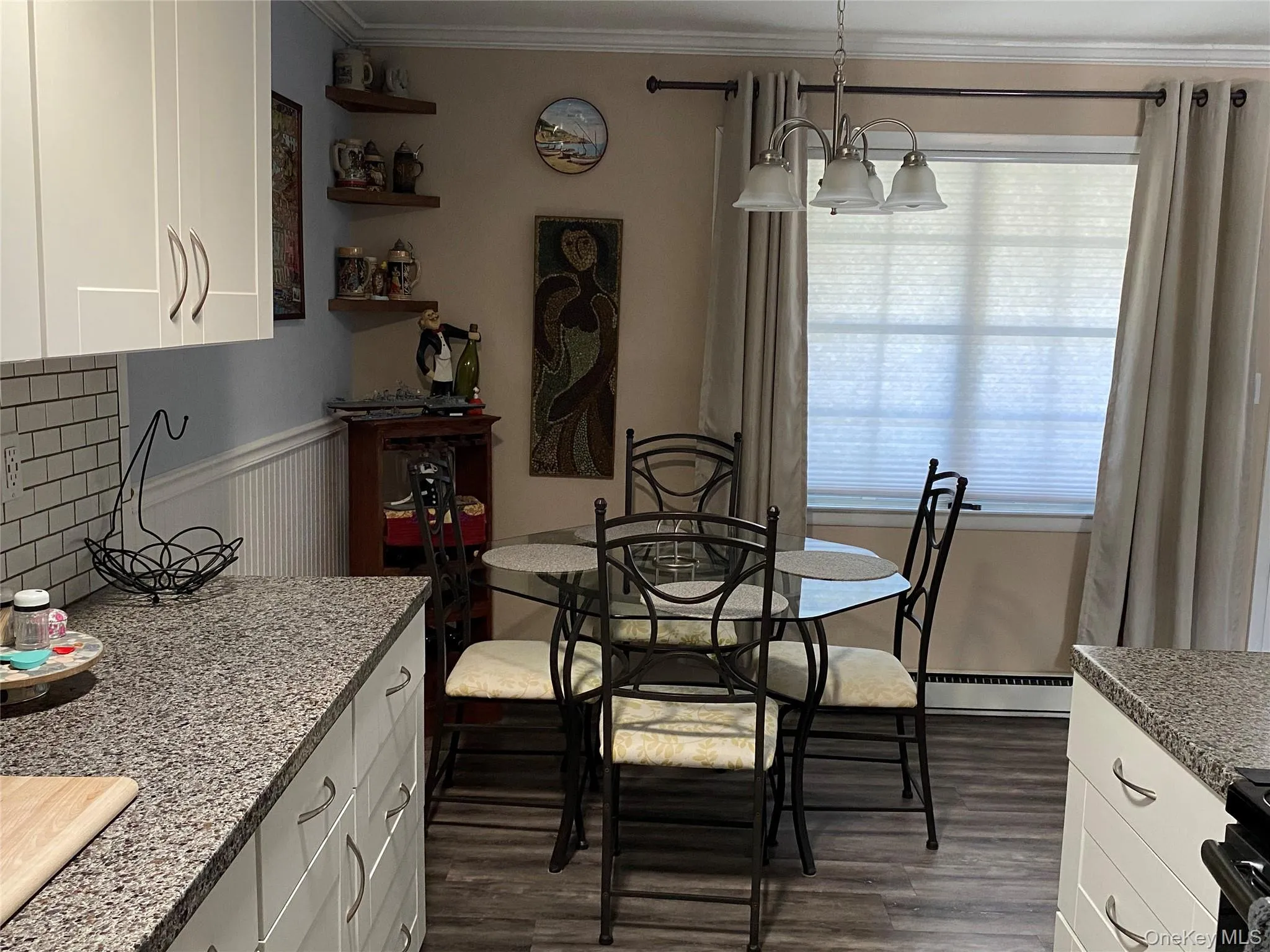 Dining space featuring dark wood-style flooring, a baseboard heating unit, ornamental molding, and a chandelier Dining space featuring dark wood-style flooring, a baseboard heating unit, ornamental molding, and a chandelier