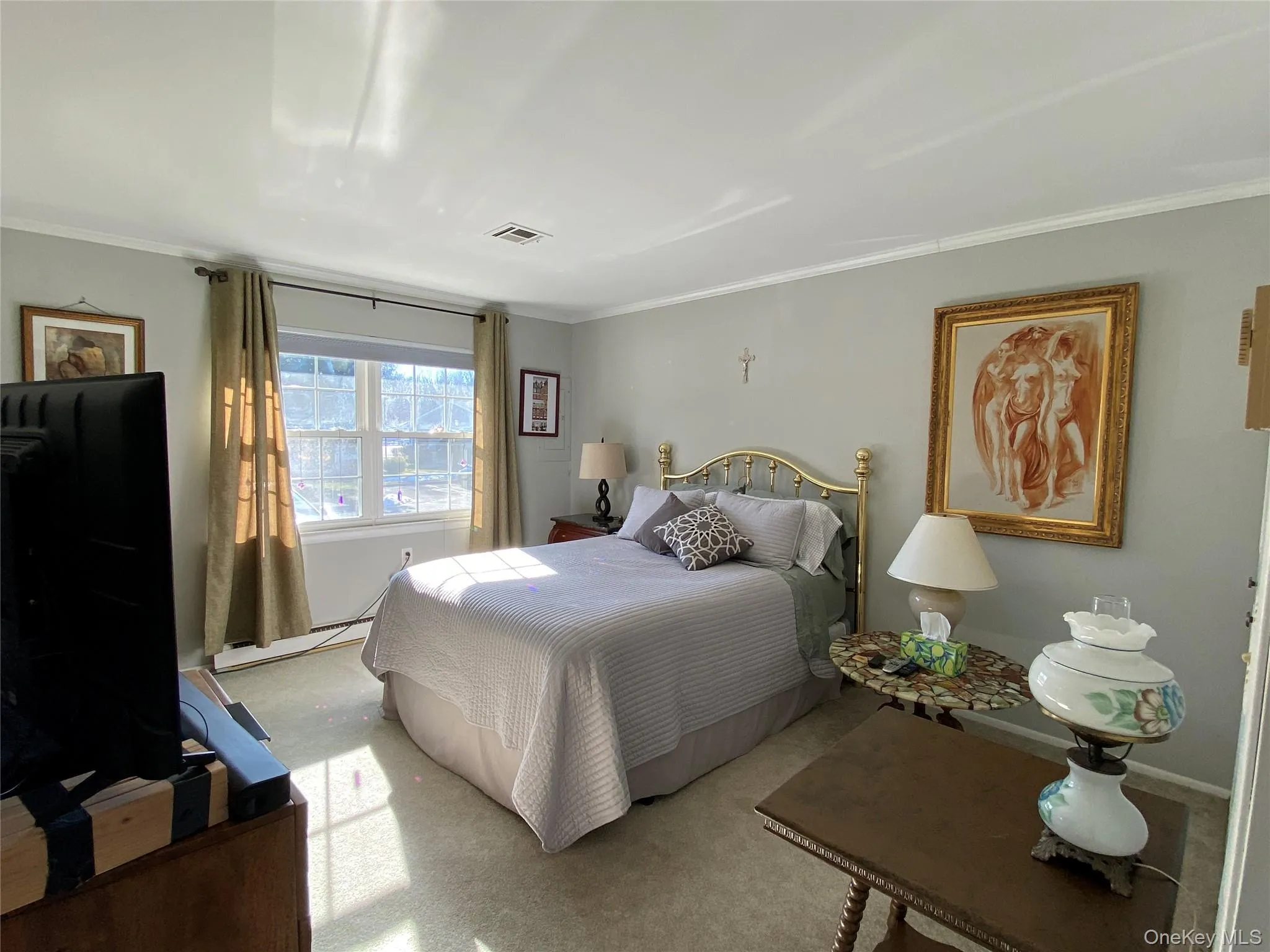 Carpeted bedroom with baseboard heating and ornamental molding Carpeted bedroom with baseboard heating and ornamental molding