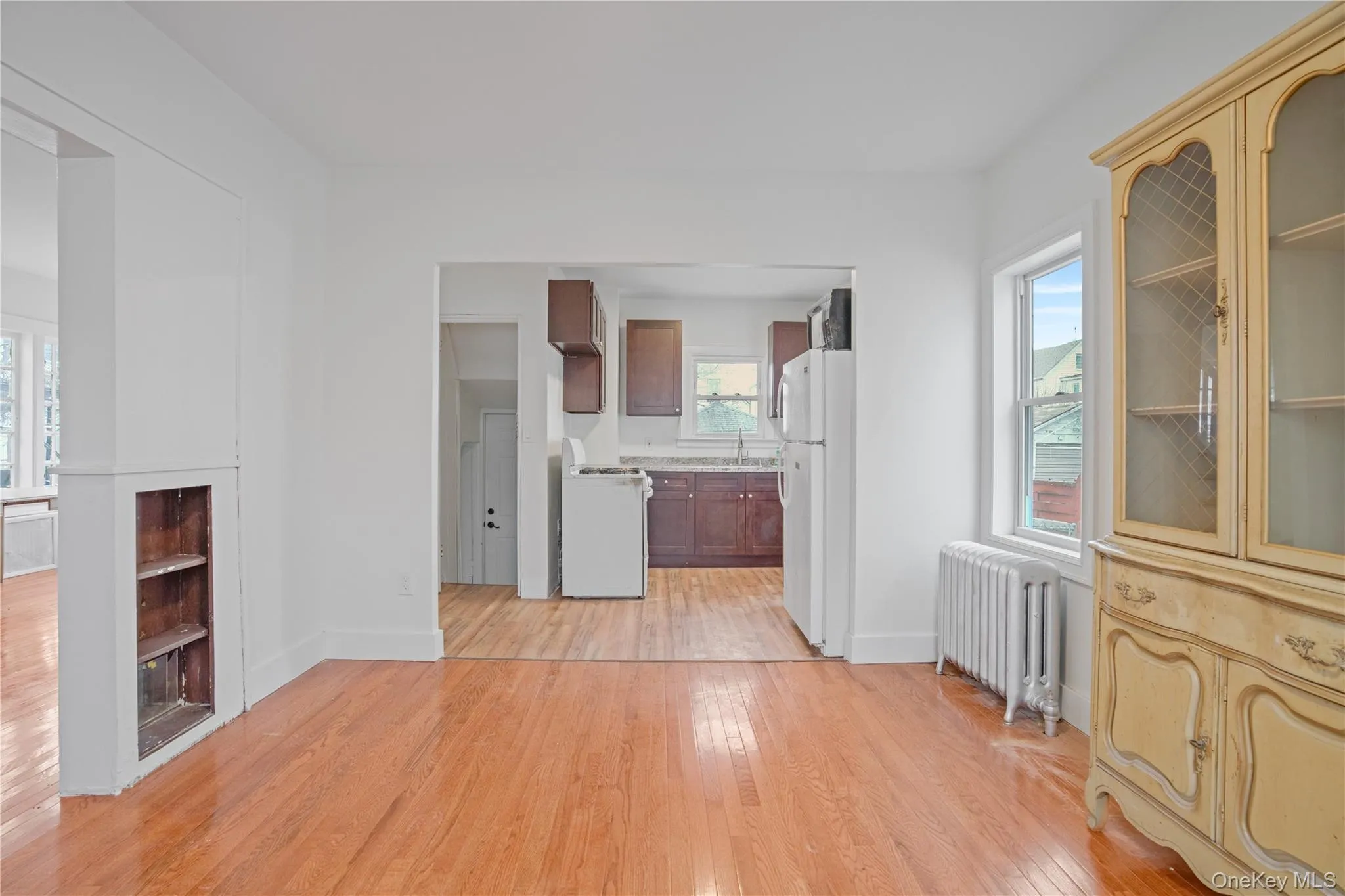 Unfurnished living room featuring radiator heating unit and light wood-style floors Unfurnished living room featuring radiator heating unit and light wood-style floors