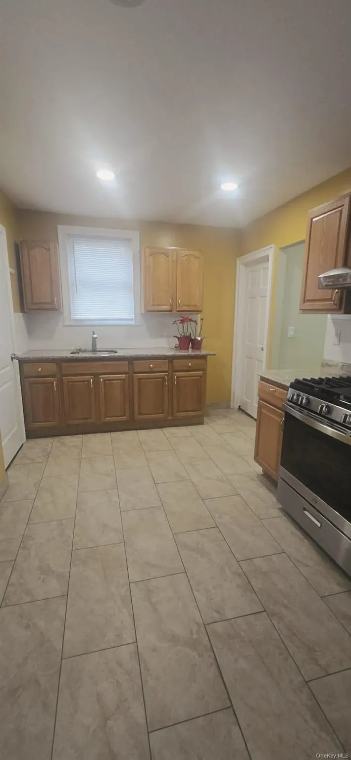 Kitchen featuring stainless steel gas range oven, light countertops, recessed lighting, and brown cabinets Kitchen featuring stainless steel gas range oven, light countertops, recessed lighting, and brown cabinets