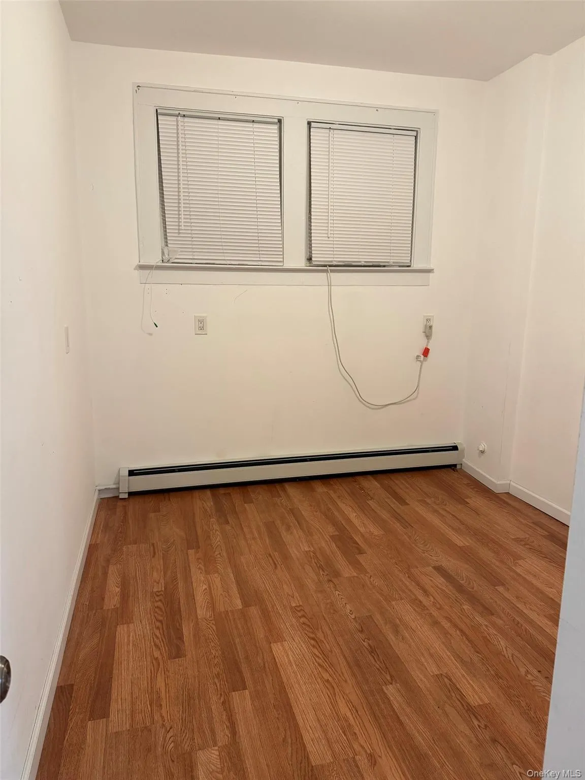 Spare room with light wood-style flooring and a baseboard radiator Spare room with light wood-style flooring and a baseboard radiator