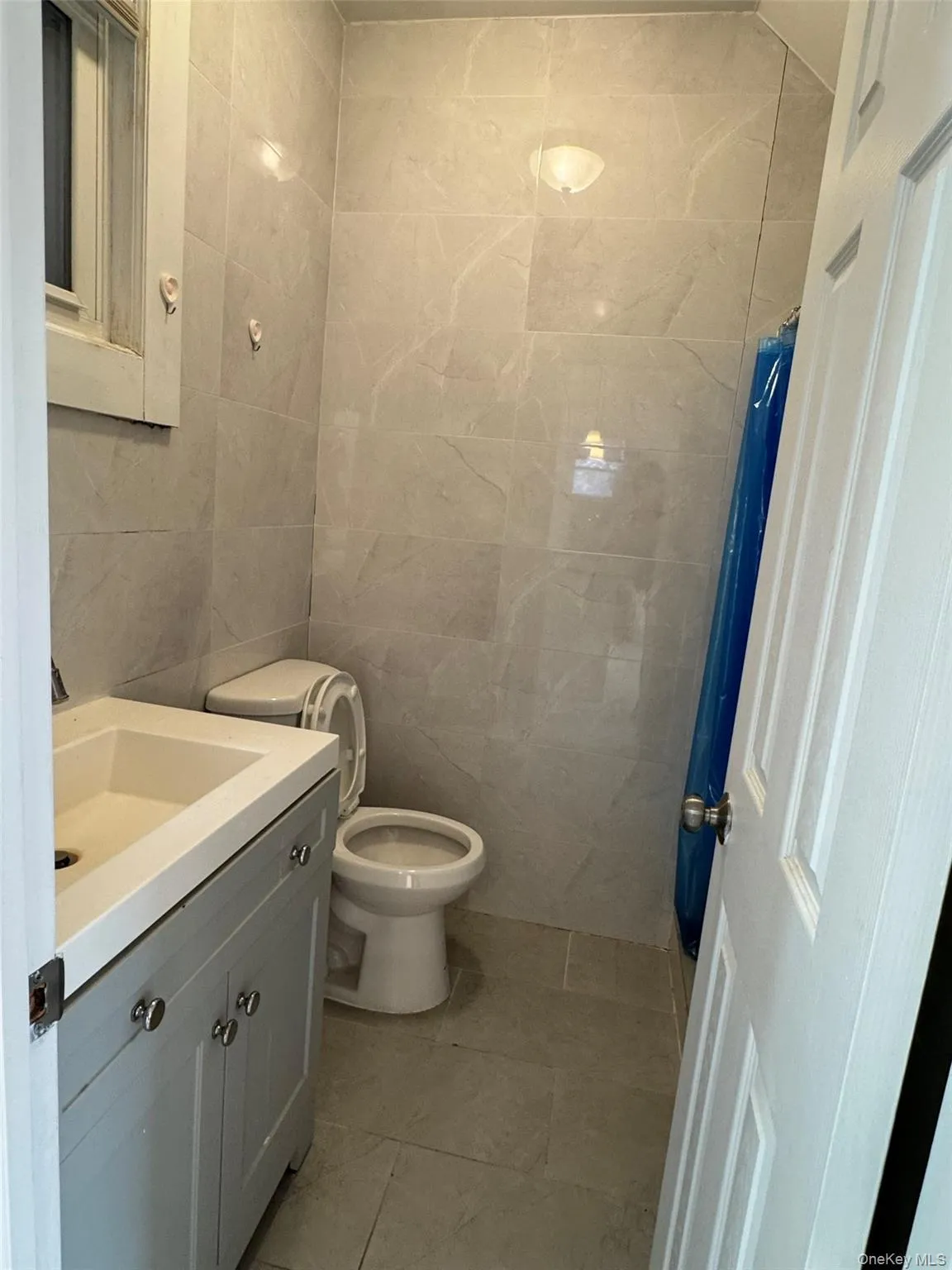 Full bathroom featuring tile walls, a shower with shower curtain, vanity, and light tile patterned floors Full bathroom featuring tile walls, a shower with shower curtain, vanity, and light tile patterned floors