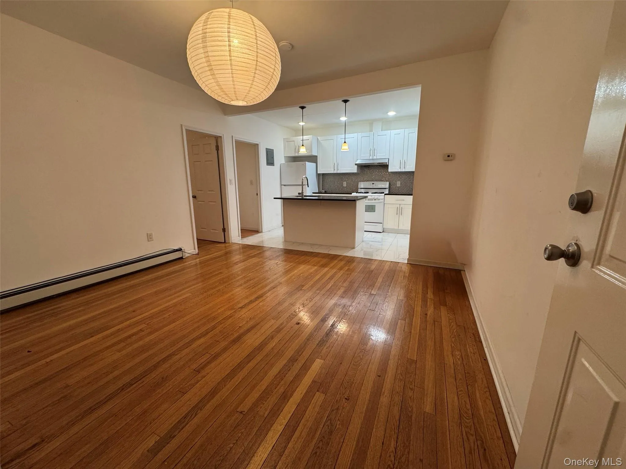 Unfurnished living room featuring light wood-style floors and a baseboard radiator Unfurnished living room featuring light wood-style floors and a baseboard radiator
