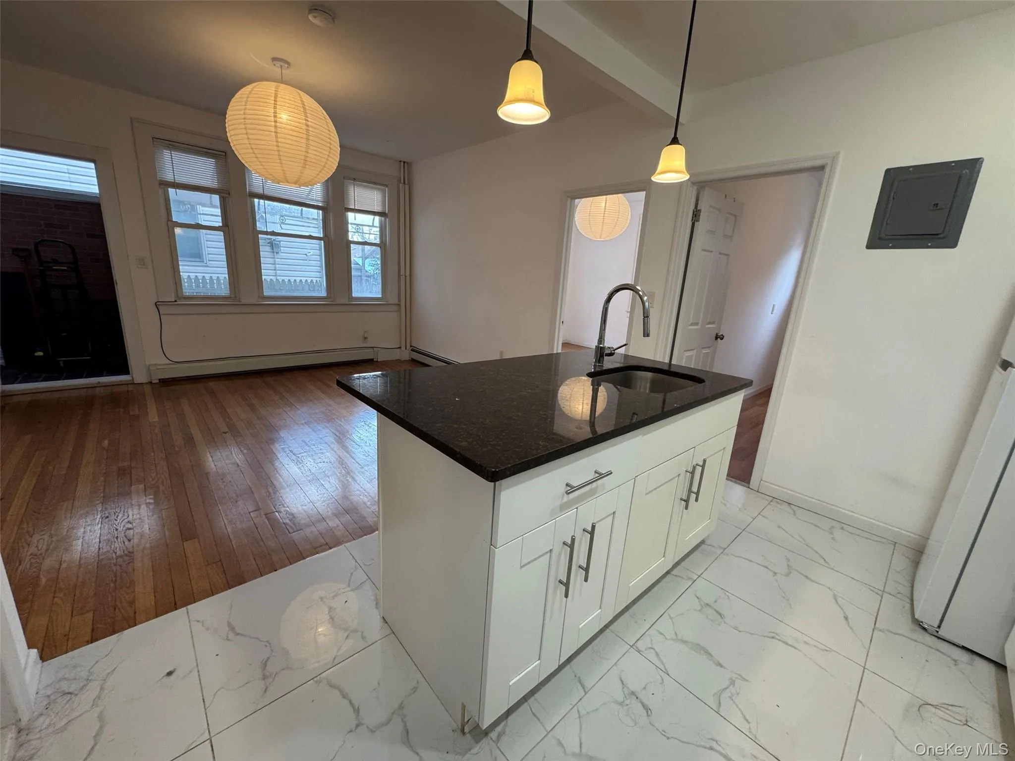 Kitchen with white cabinetry, dark stone counters, decorative light fixtures, and light marble finish flooring Kitchen with white cabinetry, dark stone counters, decorative light fixtures, and light marble finish flooring