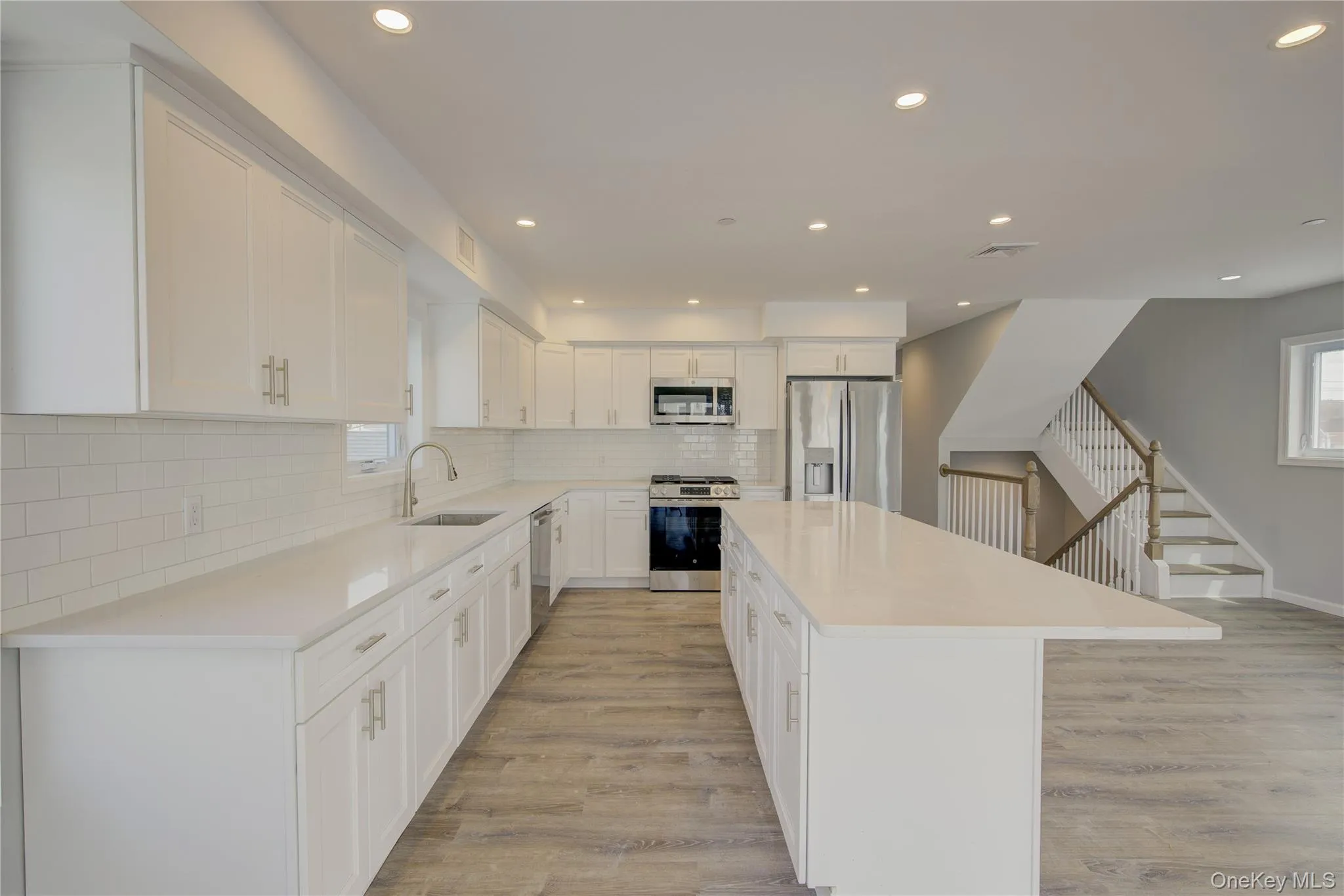 Kitchen featuring stainless steel appliances, recessed lighting, a center island, decorative backsplash, and light wood-type flooring Kitchen featuring stainless steel appliances, recessed lighting, a center island, decorative backsplash, and light wood-type flooring