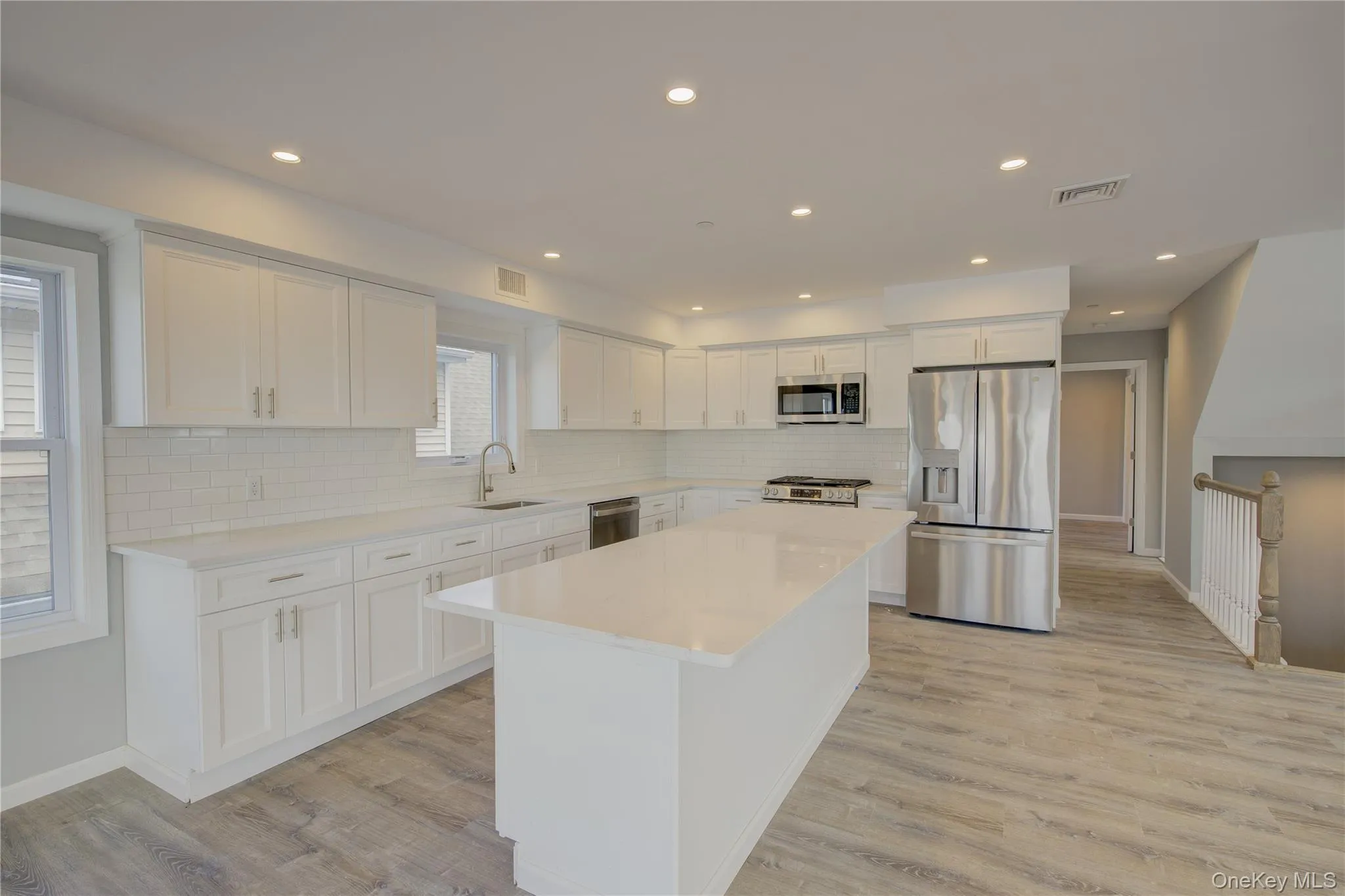 Kitchen with appliances with stainless steel finishes, white cabinets, light countertops, light wood finished floors, and recessed lighting Kitchen with appliances with stainless steel finishes, white cabinets, light countertops, light wood finished floors, and recessed lighting