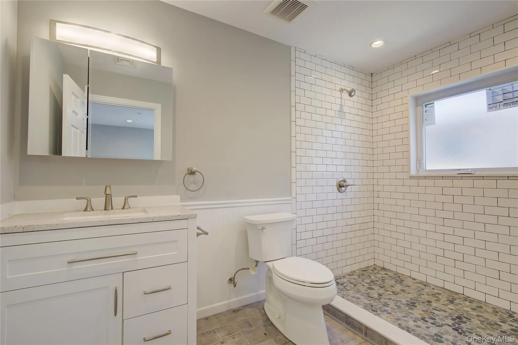 Full bathroom featuring a tile shower, vanity, wainscoting, and recessed lighting Full bathroom featuring a tile shower, vanity, wainscoting, and recessed lighting
