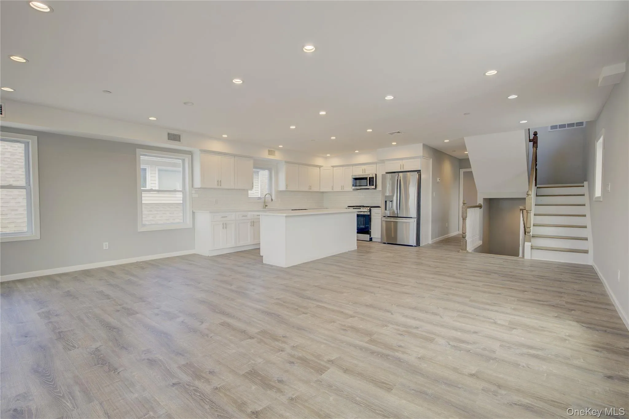 Unfurnished living room with recessed lighting, stairway, and light wood-style flooring Unfurnished living room with recessed lighting, stairway, and light wood-style flooring