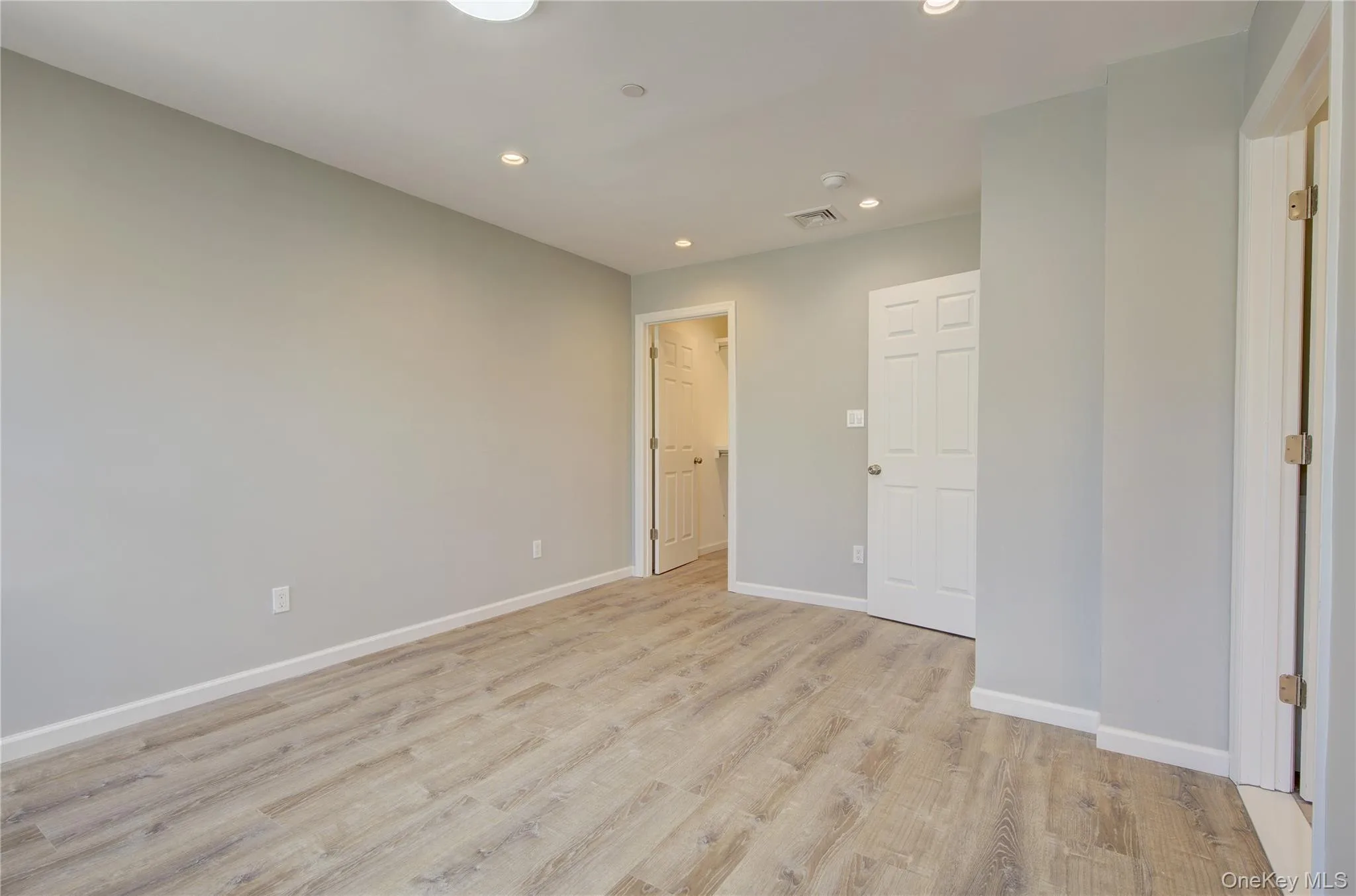 Unfurnished bedroom featuring recessed lighting, light wood-type flooring, and a spacious closet Unfurnished bedroom featuring recessed lighting, light wood-type flooring, and a spacious closet