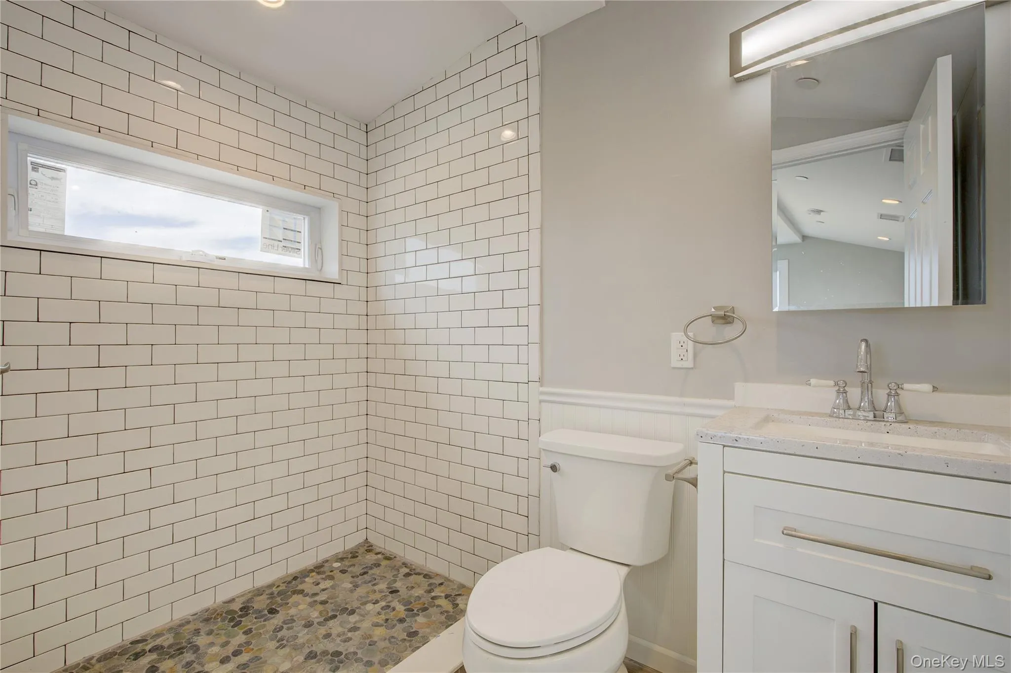 Bathroom featuring vanity, a wainscoted wall, and tiled shower Bathroom featuring vanity, a wainscoted wall, and tiled shower