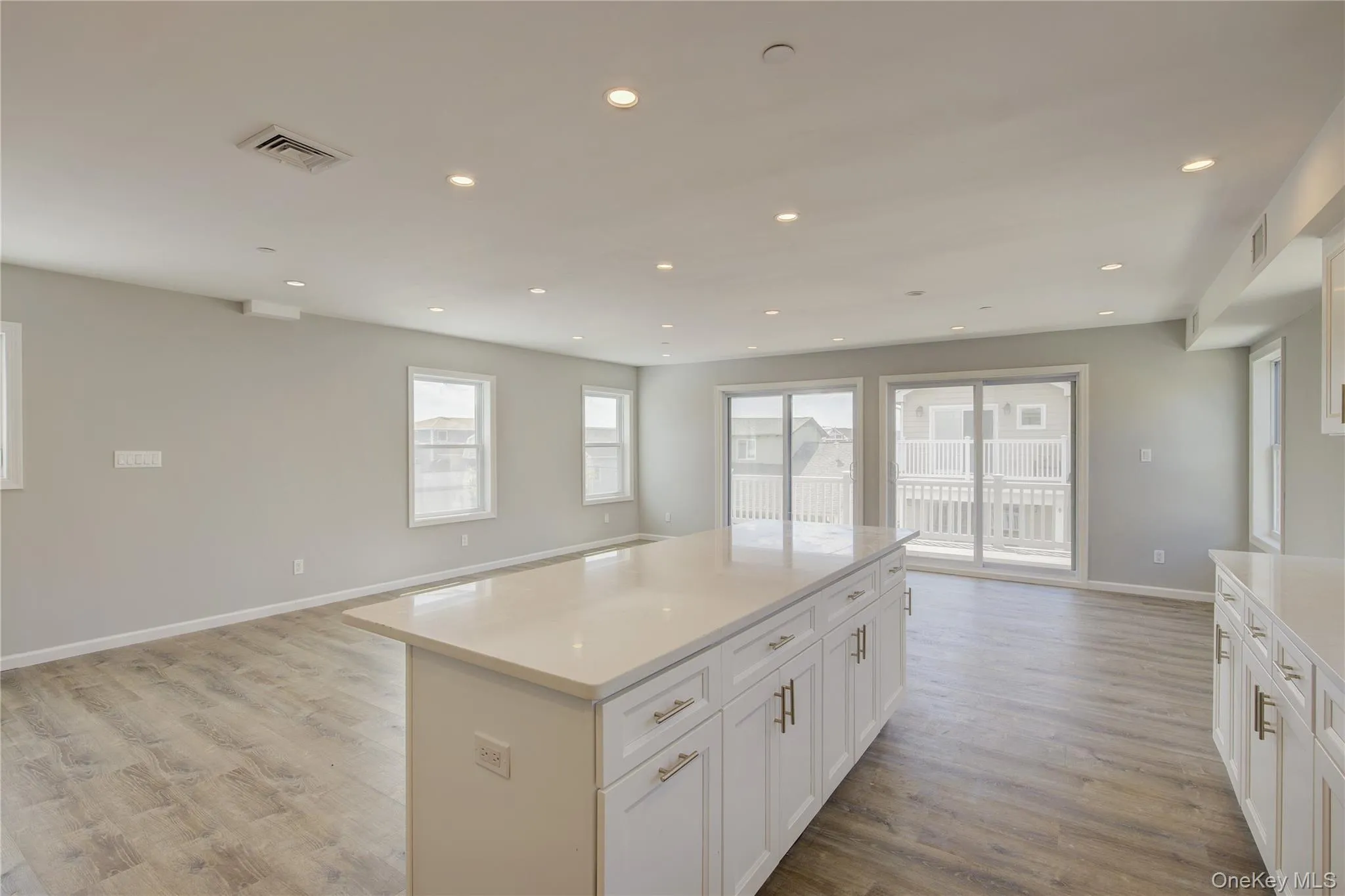 Kitchen with open floor plan, recessed lighting, light wood finished floors, a center island, and white cabinets Kitchen with open floor plan, recessed lighting, light wood finished floors, a center island, and white cabinets