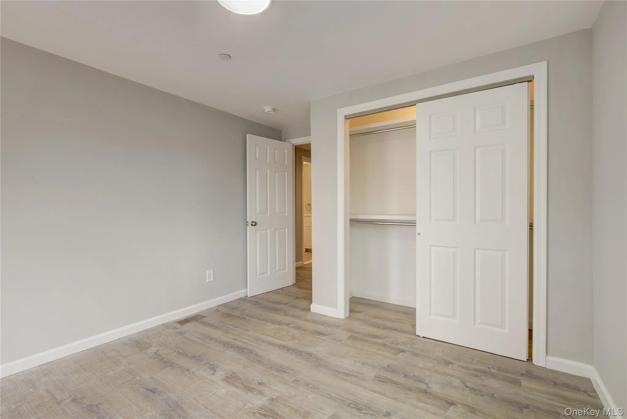 Unfurnished bedroom featuring wood finished floors and a closet Unfurnished bedroom featuring wood finished floors and a closet