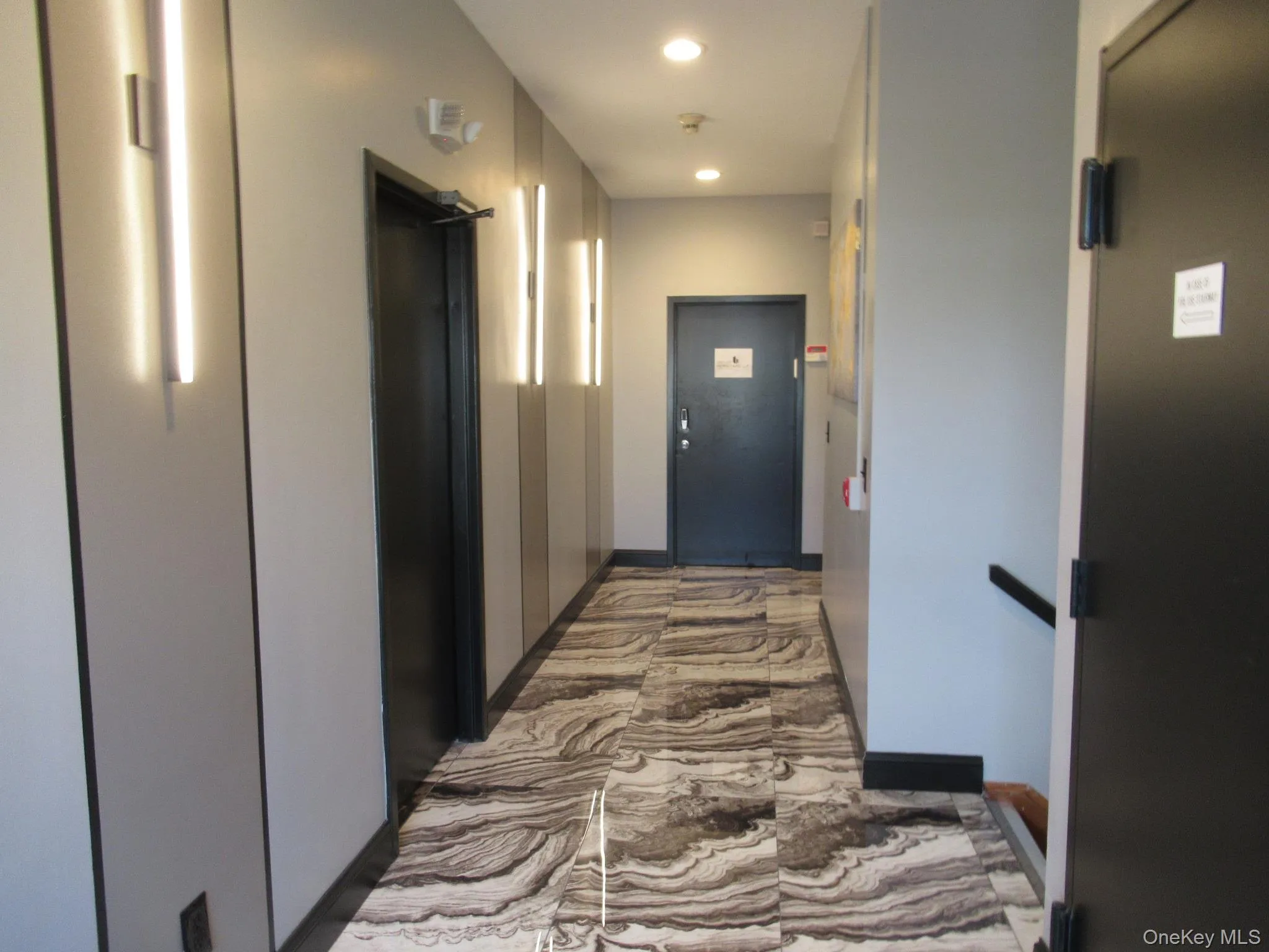 Hall with elevator, recessed lighting, and marble look tile flooring Hall with elevator, recessed lighting, and marble look tile flooring