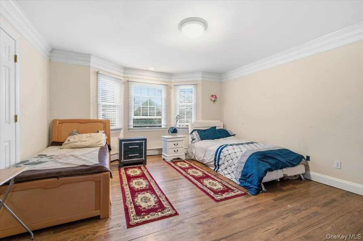 2nd floor Bedroom #4 with crown molding, wood finished floors, and a baseboard heating unit 2nd floor Bedroom #4 with crown molding, wood finished floors, and a baseboard heating unit