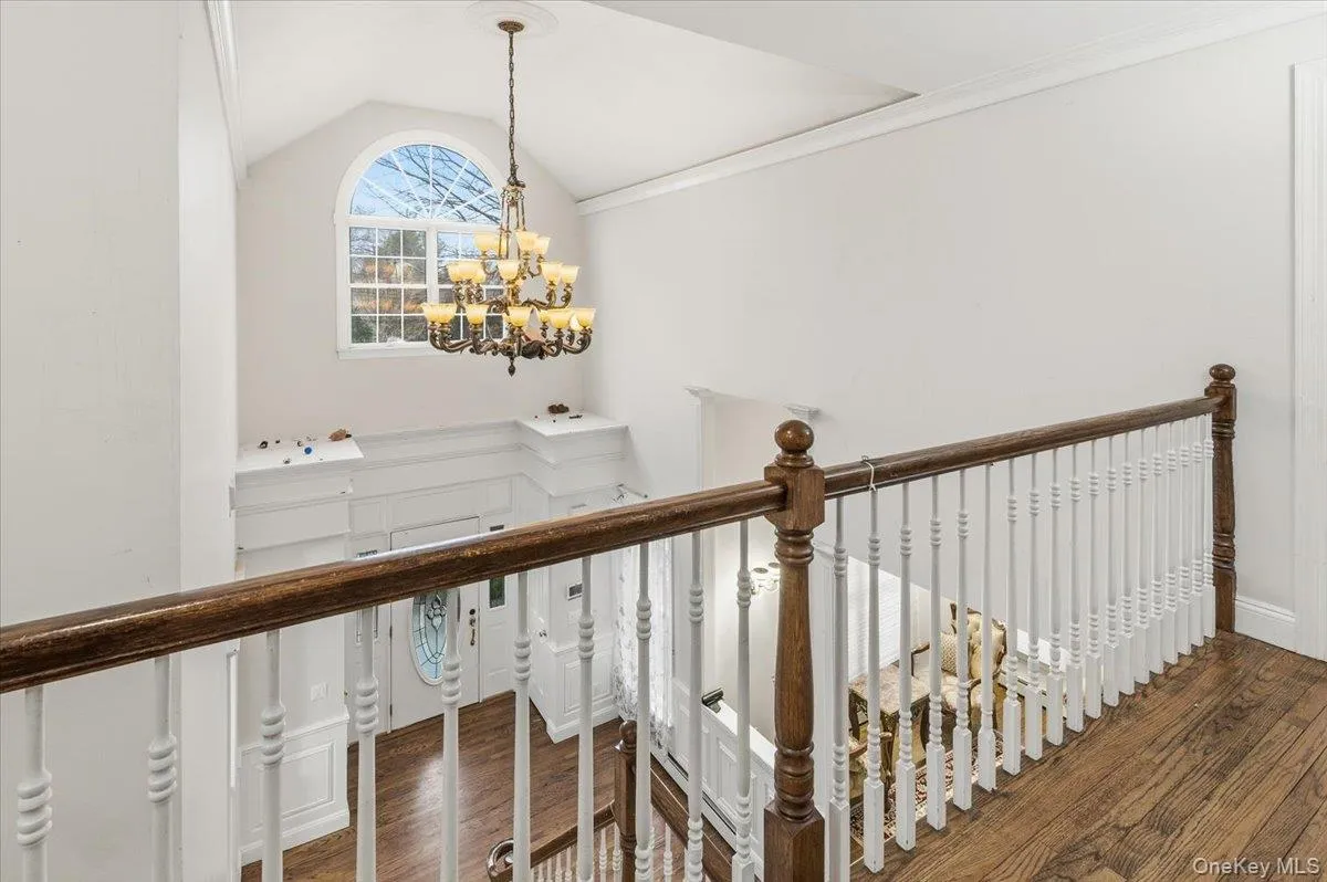 Staircase with a chandelier, wood finished floors, and crown molding Staircase with a chandelier, wood finished floors, and crown molding