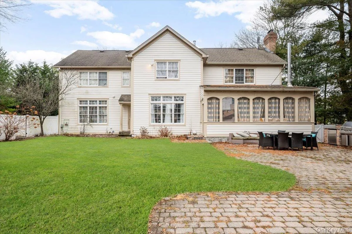 Rear view of property featuring a chimney, a sunroom, a patio area, and a shingled roof Rear view of property featuring a chimney, a sunroom, a patio area, and a shingled roof