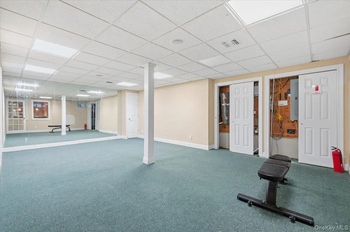 Basement Exercise area featuring a drop ceiling and electric panel Basement Exercise area featuring a drop ceiling and electric panel