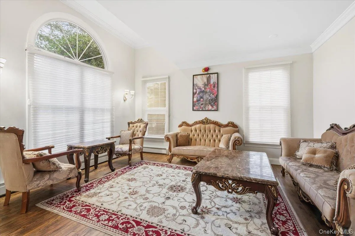 Formal Living area with ornamental molding, wood finished floors, healthy amount of natural light, and a baseboard heating unit Formal Living area with ornamental molding, wood finished floors, healthy amount of natural light, and a baseboard heating unit