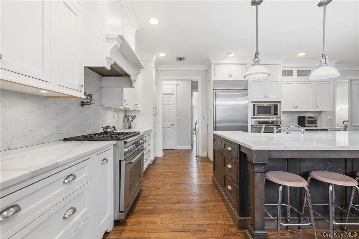 Kitchen featuring a kitchen bar, light stone counters, white cabinetry, crown molding, and recessed lighting Kitchen featuring a kitchen bar, light stone counters, white cabinetry, crown molding, and recessed lighting