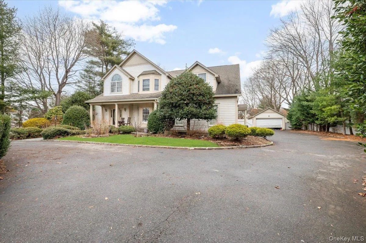 View of front of home with covered porch, a garage, an outbuilding, and a shingled roof View of front of home with covered porch, a garage, an outbuilding, and a shingled roof