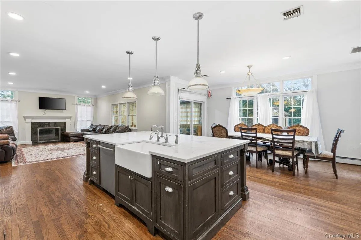 Kitchen with crown molding, open floor plan, light stone counters, a glass covered fireplace, and dark wood finished floors Kitchen with crown molding, open floor plan, light stone counters, a glass covered fireplace, and dark wood finished floors